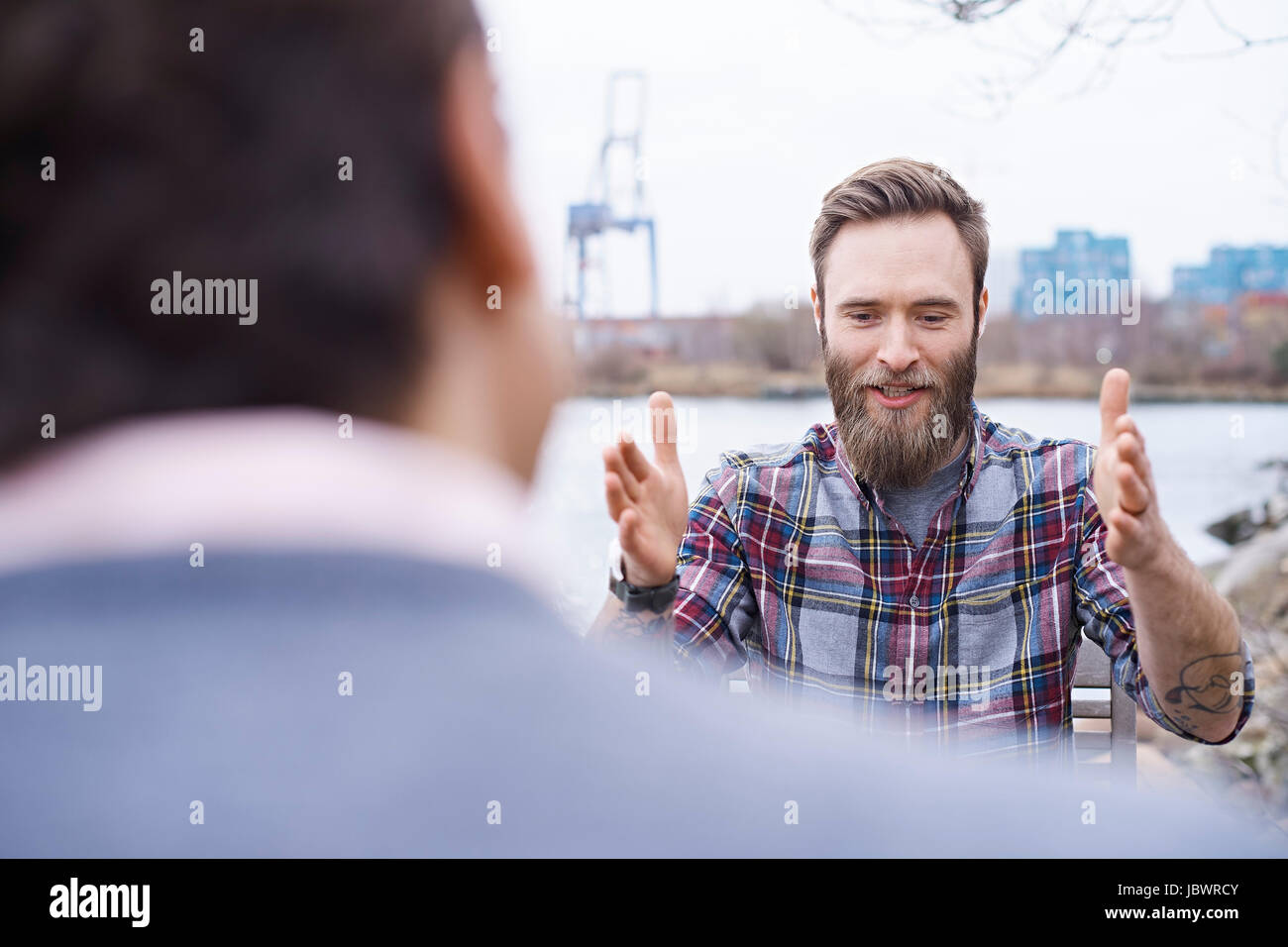Sulla spalla vista del designer maschio avente la discussione sul lungomare al di fuori dell design studio Foto Stock