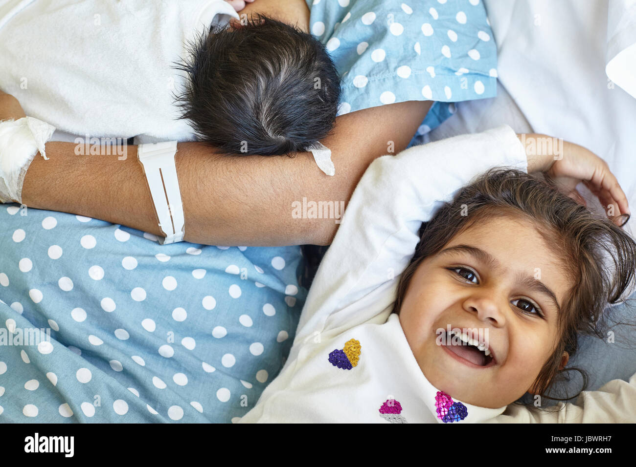 Giovane ragazza distesa con Madre e Madre holding neonato boy, metà sezione Foto Stock