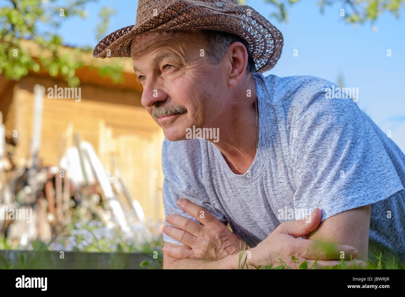 Ritratto di bella anziano uomo con i baffi. Si trova sull'erba sorridente e guardando la telecamera. Foto Stock