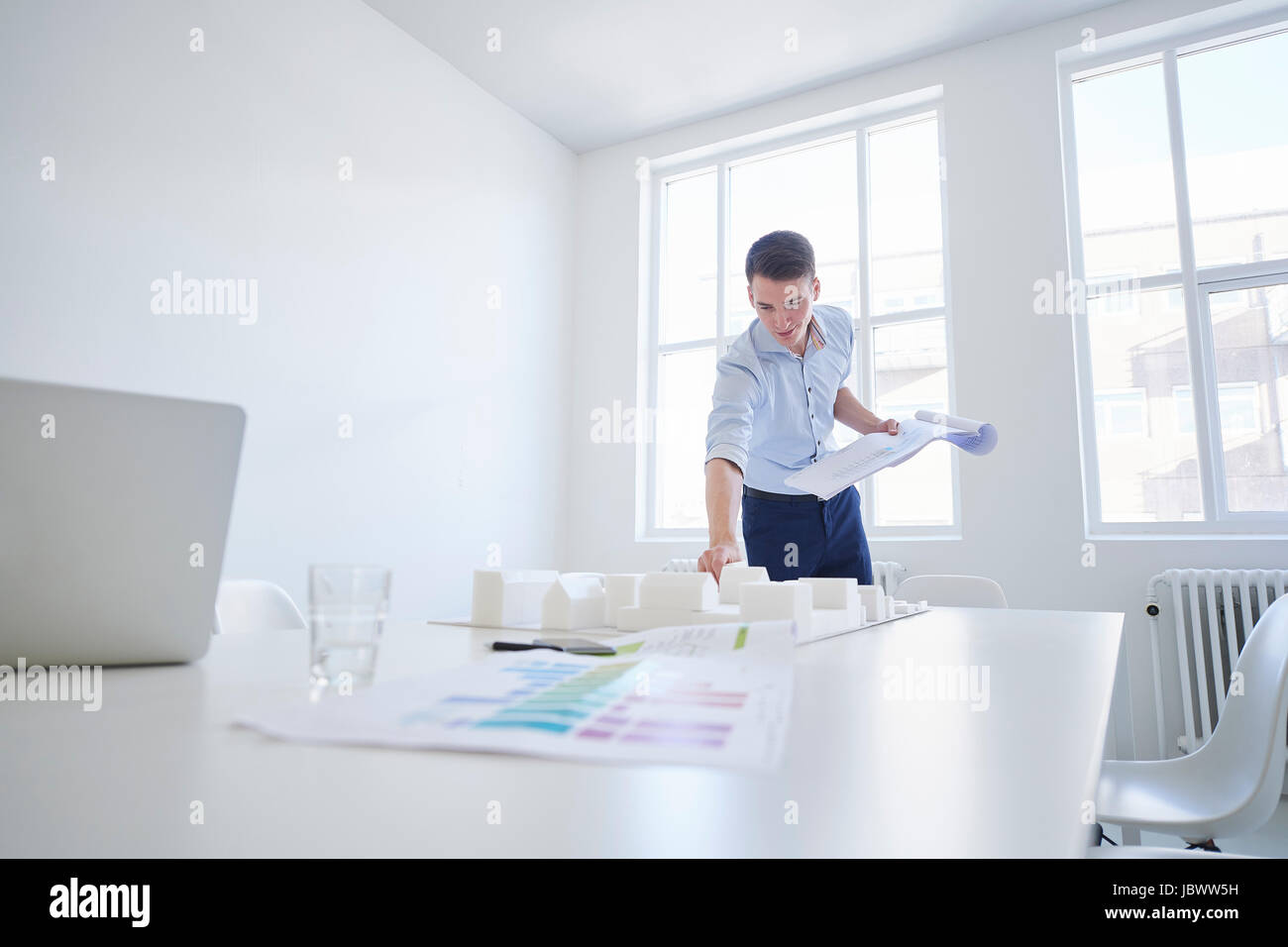 L'architetto in ufficio con blueprint guardando al modello architettonico Foto Stock