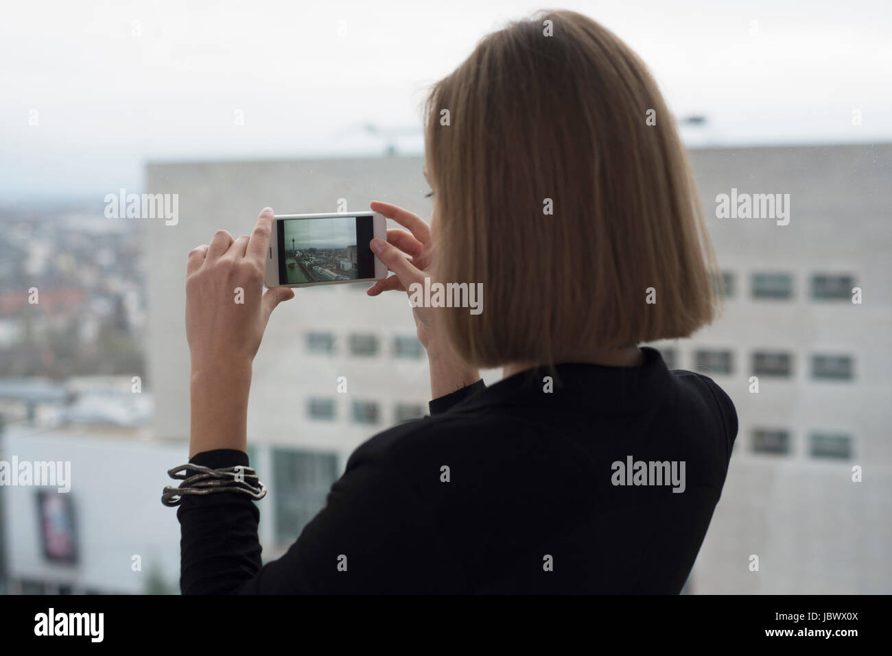 Giovane imprenditrice fotografando attraverso la finestra di ufficio Foto Stock