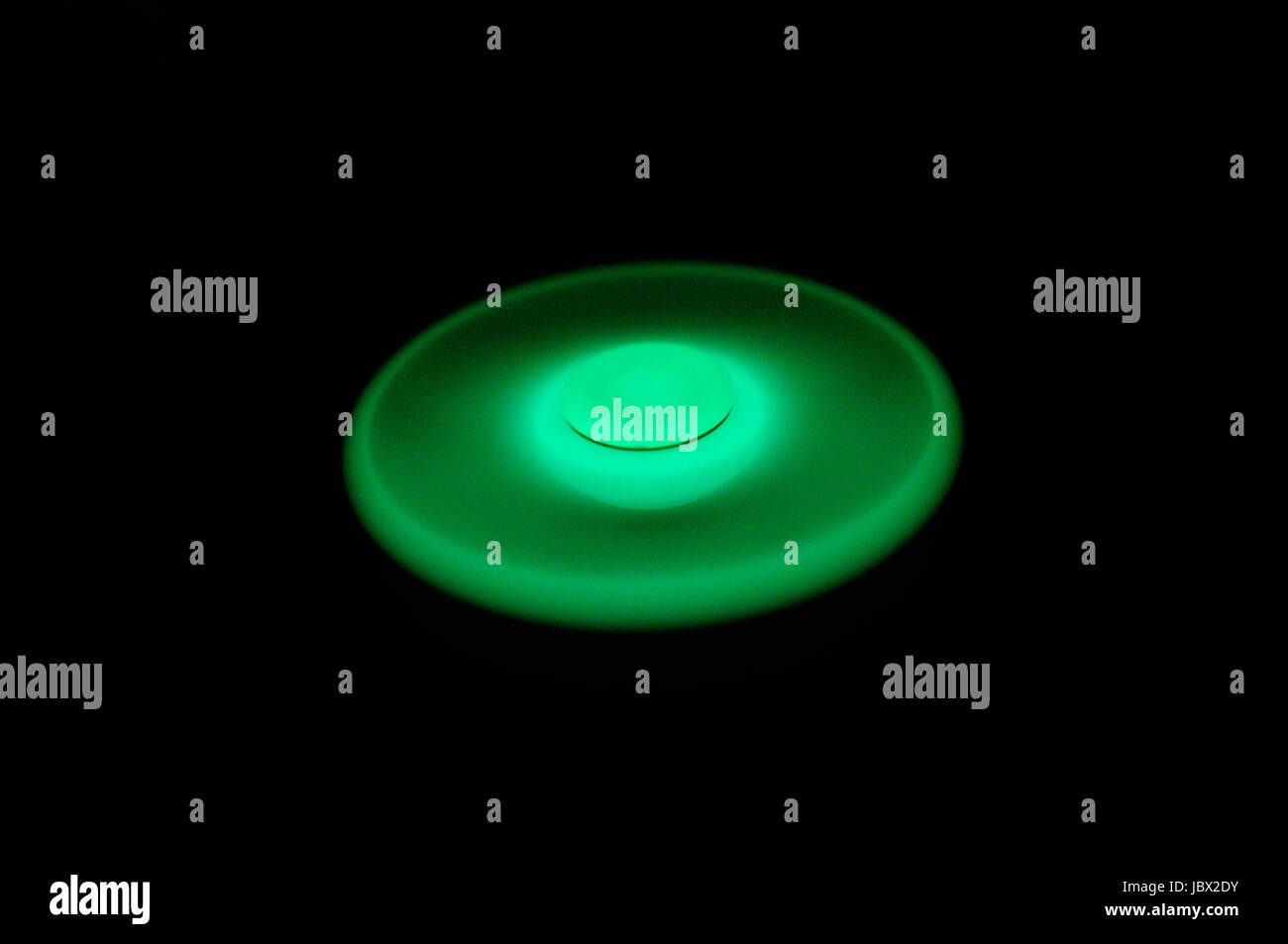 Incandescente verde nel buio agitano: spinner la filatura su sfondo nero Foto Stock
