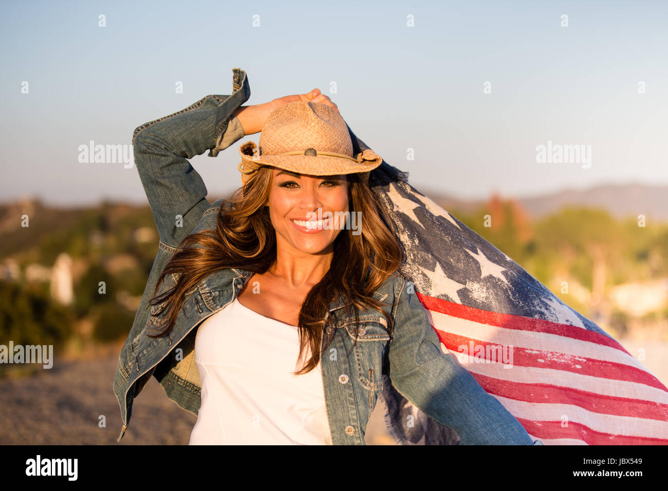 Ritratto di donna matura, all'aperto, tenendo bandiera americana, sorridente Foto Stock