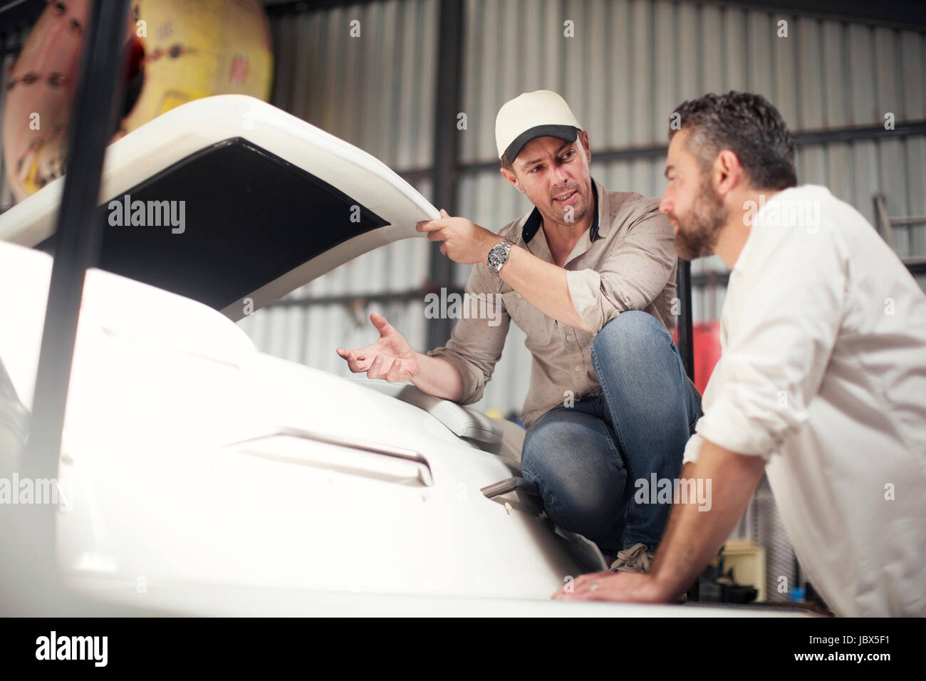Due uomini controllo barca carrozzeria in officina di riparazione Foto Stock