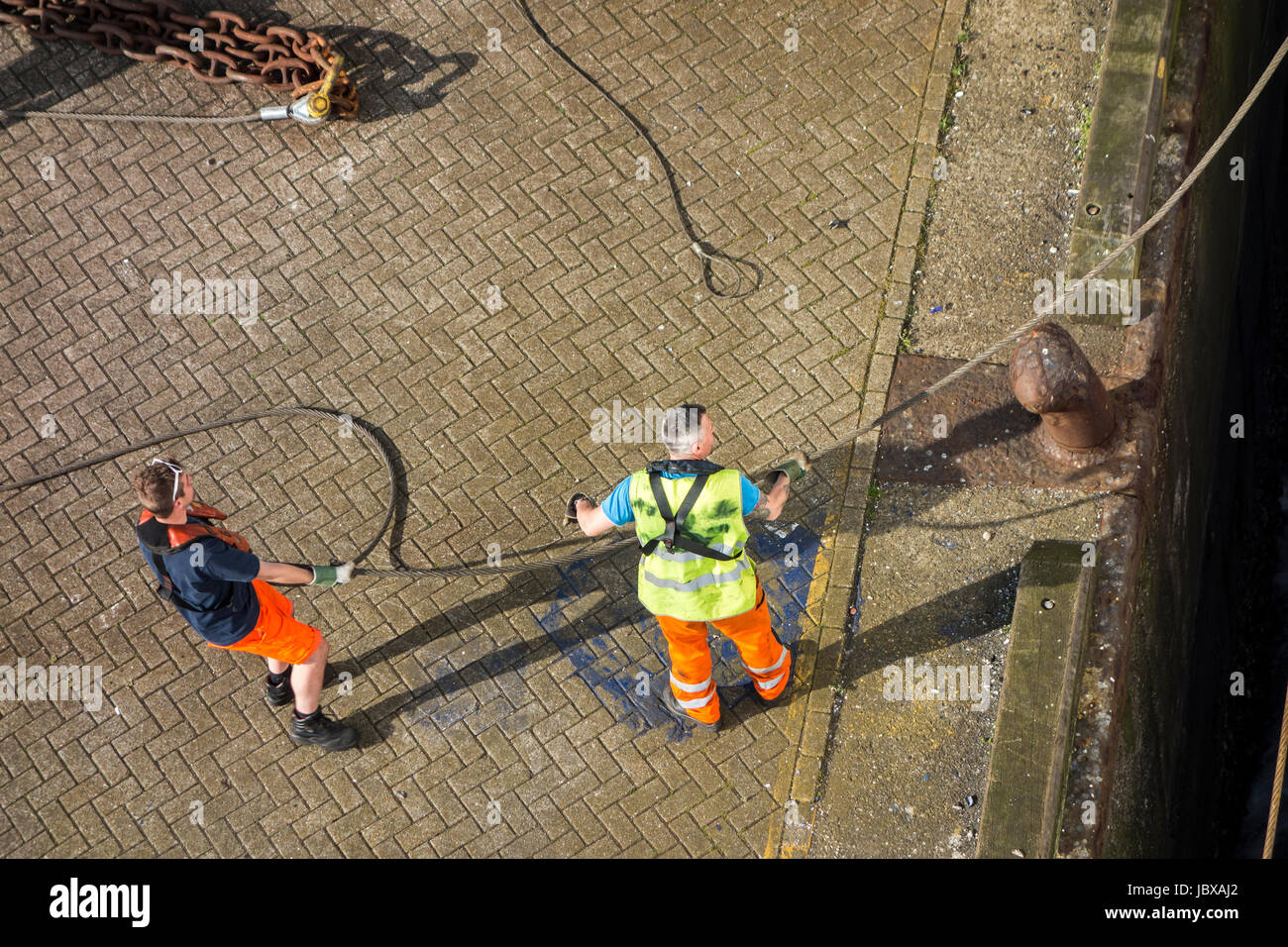 Fissaggio dei portuali nave ormeggiata's hawser a shoreside bitt sul quay in seaport's dock Foto Stock