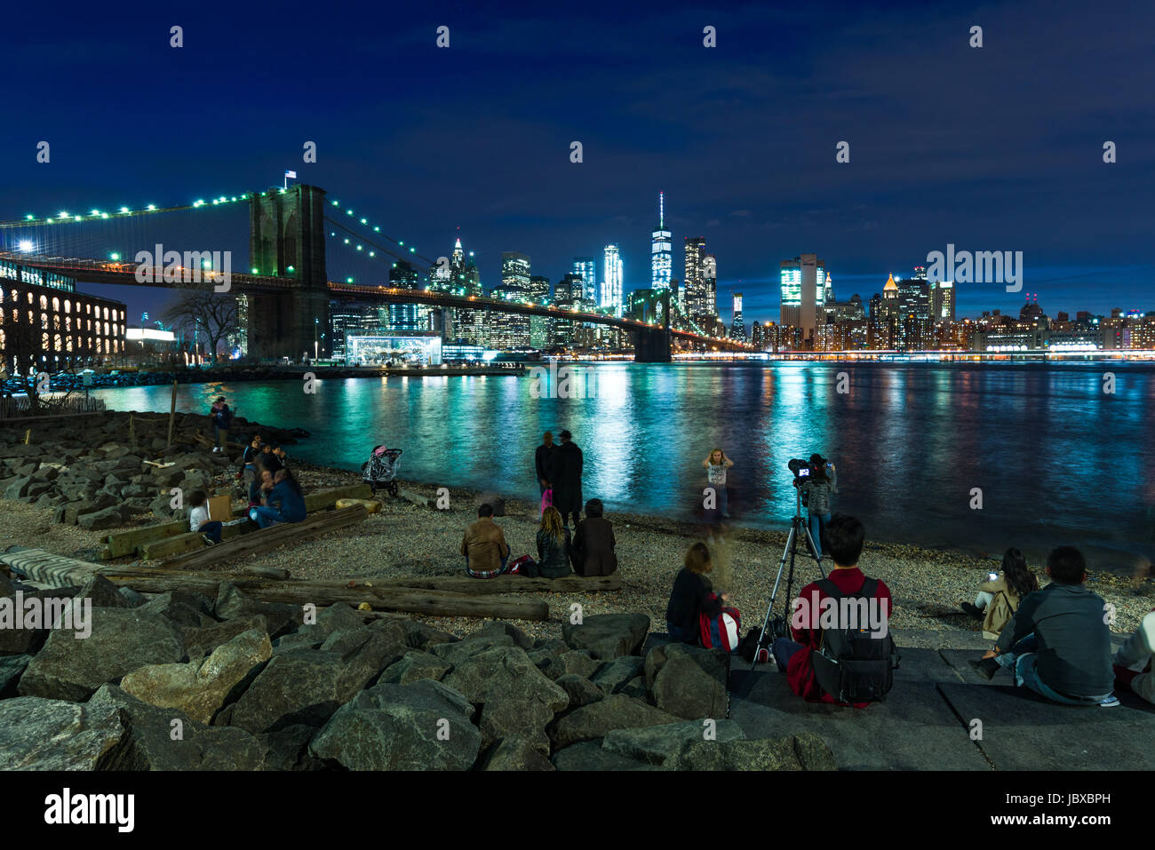 Le persone che si godono la vista da DUMBO verso Manhattan con il ponte di Brooklyn, New York Foto Stock