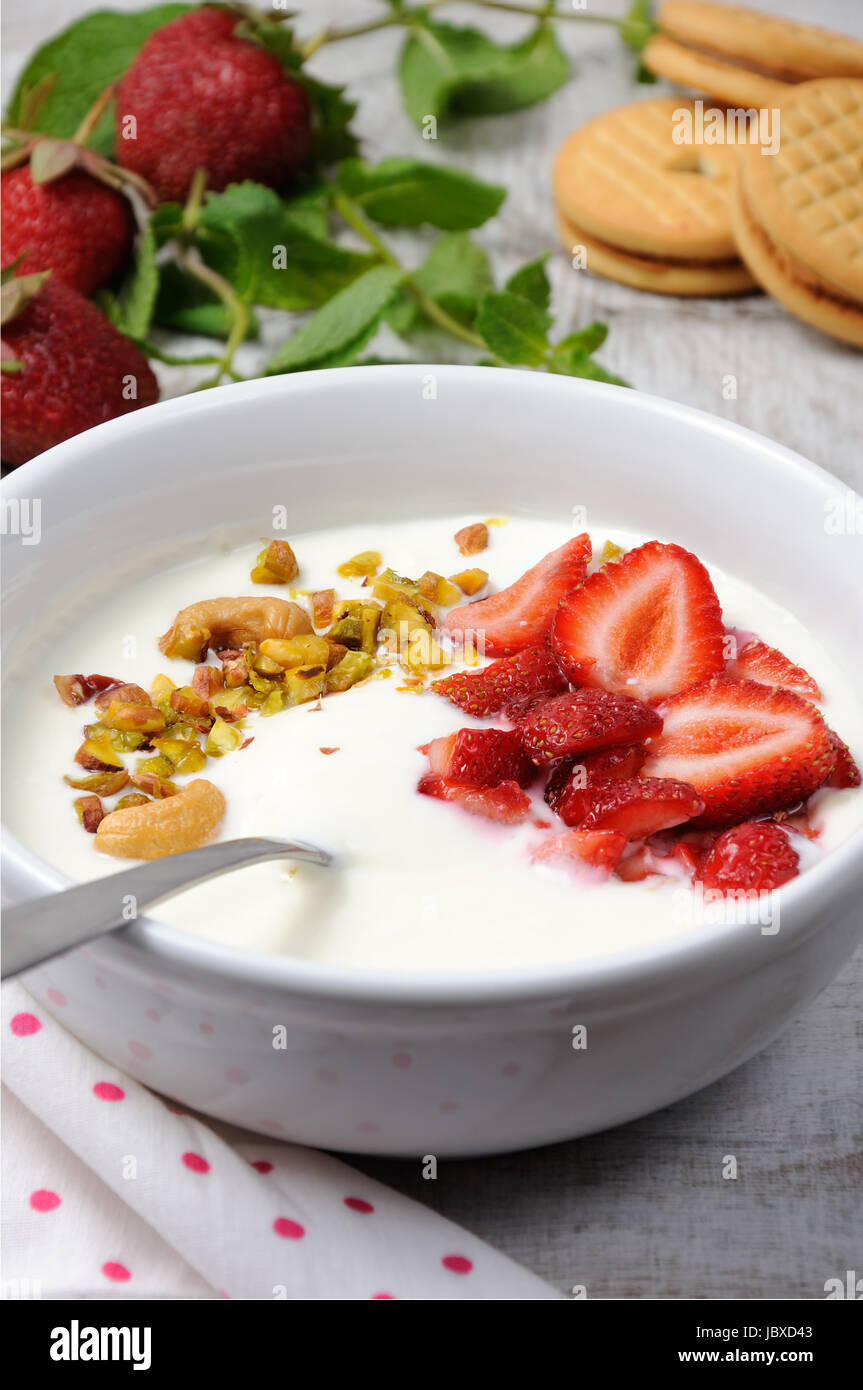 Refrigerate latticello zuppa da yogurt greco con le fragole e i pistacchi anacardi. Servire con biscotti croccanti. Colpo verticale. Foto Stock