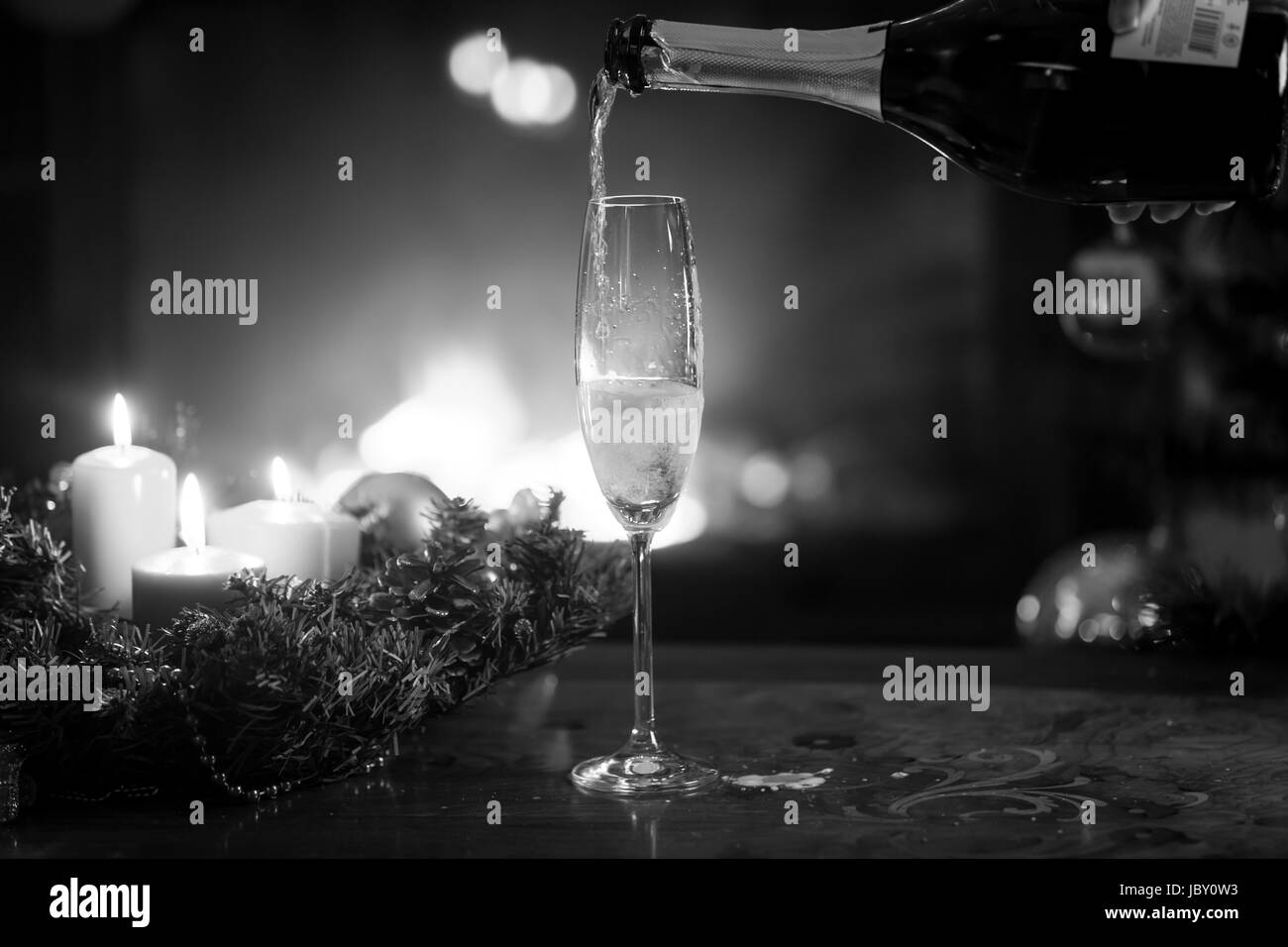 Primo piano immagine in bianco e nero di champagne flute essendo riempito dal flacone nel soggiorno alla vigilia di Natale Foto Stock