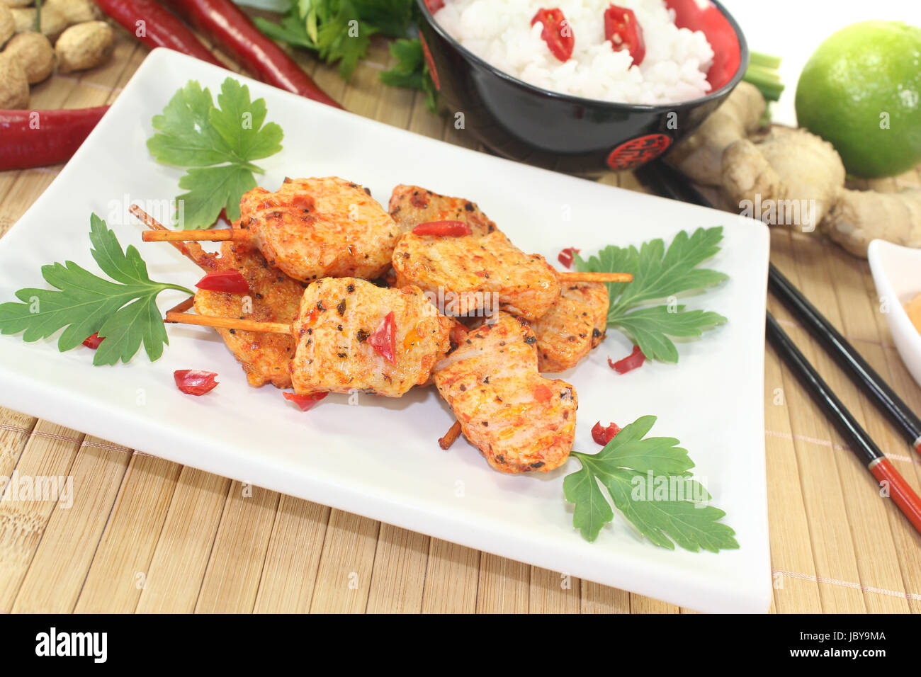 Asiatische Satè-Spieße mit Reis und Petersilie vor hellem Hintergrund Foto Stock