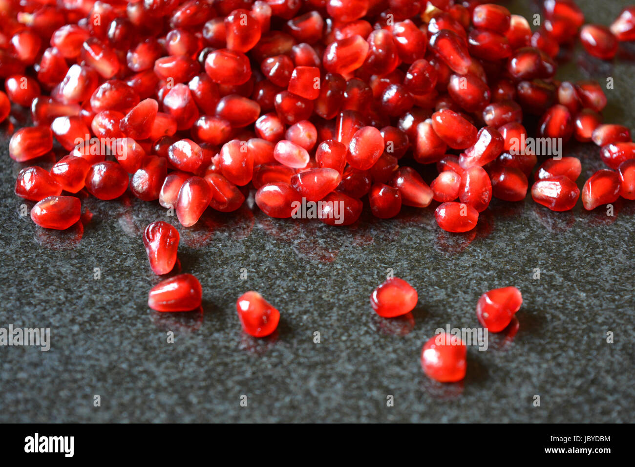 Melograno, Punica granatum, arils o semi sul granito lucido. Foto Stock