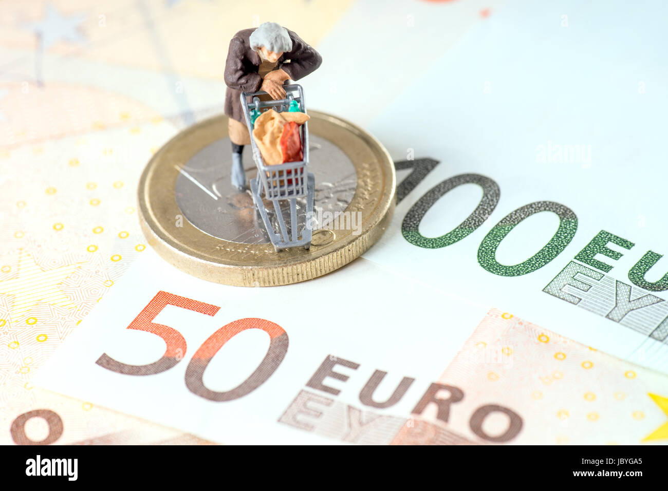Vecchia donna con carrello su una moneta in euro con banconote Foto Stock