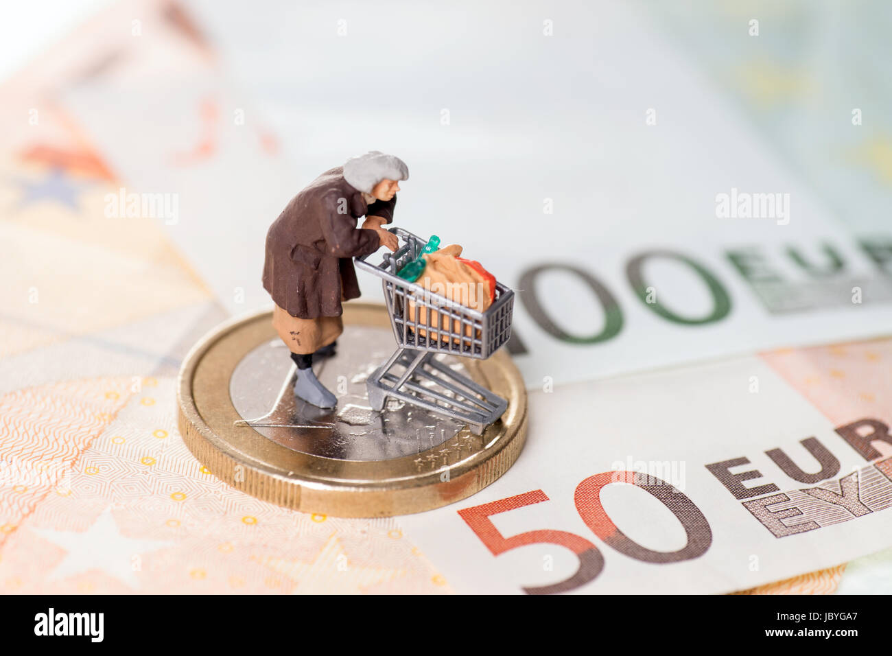 Vecchia donna con carrello su una moneta in euro con banconote Foto Stock