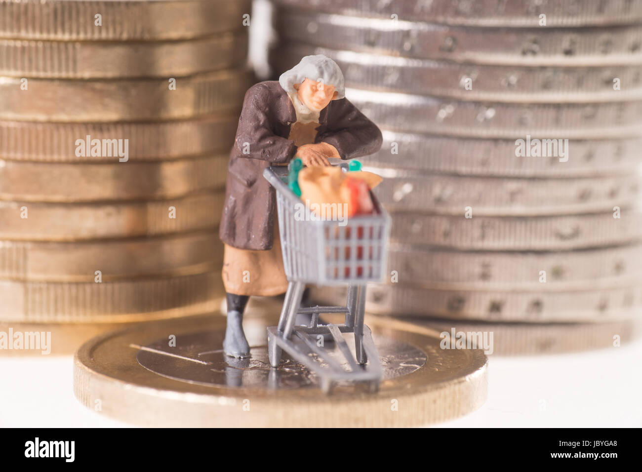 Vecchia donna con carrello su una moneta in euro Foto Stock