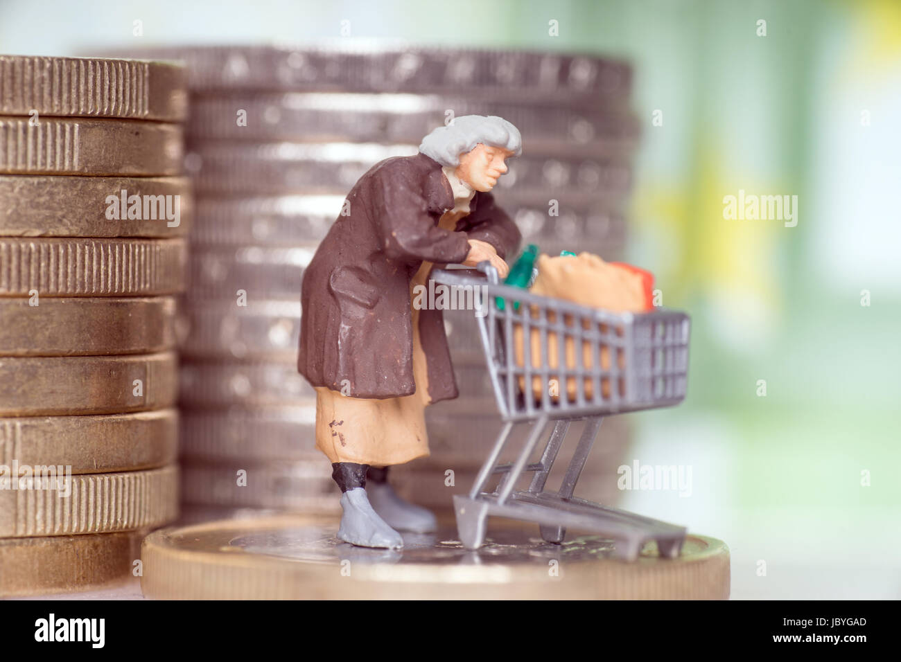 Vecchia donna con carrello su una moneta in euro Foto Stock