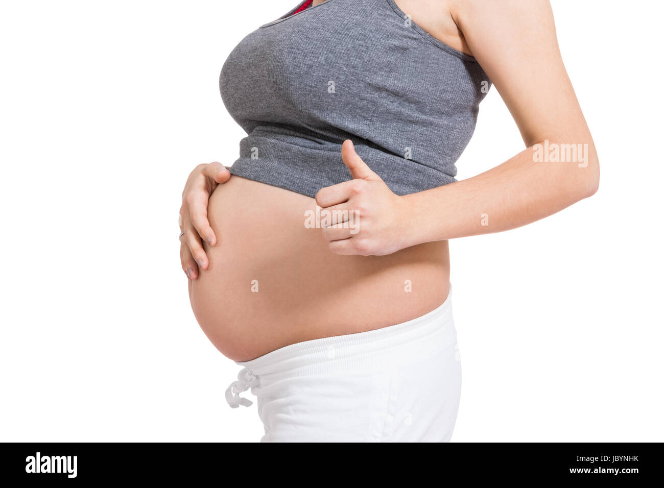 Junge frau mit Babybauch in erwartungsvoller Haltung als Nahaufnahme isoliert vor weißem Hintergrund Foto Stock