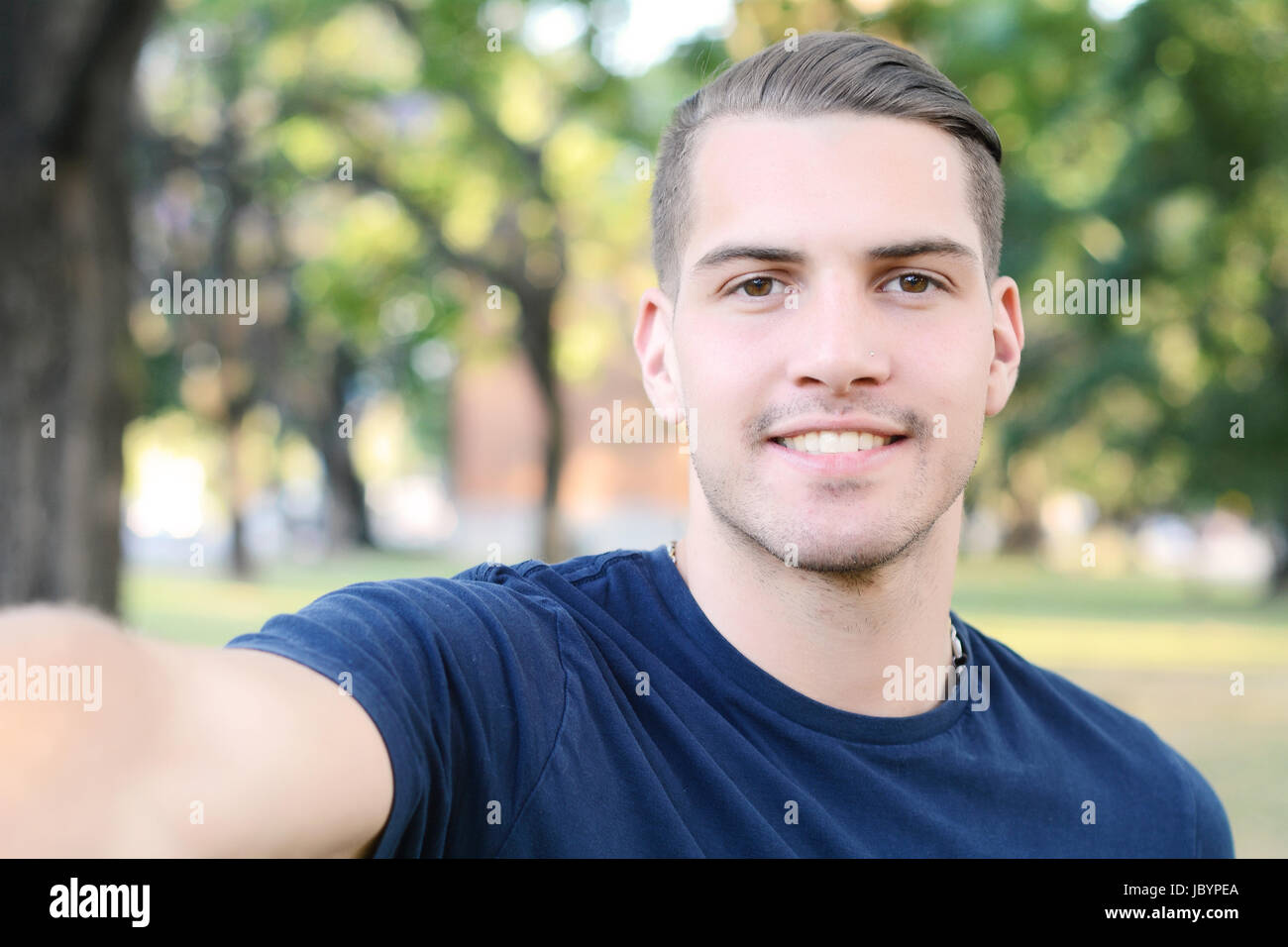 Giovane uomo latino tenendo un selfie in un parco. All'esterno. Foto Stock