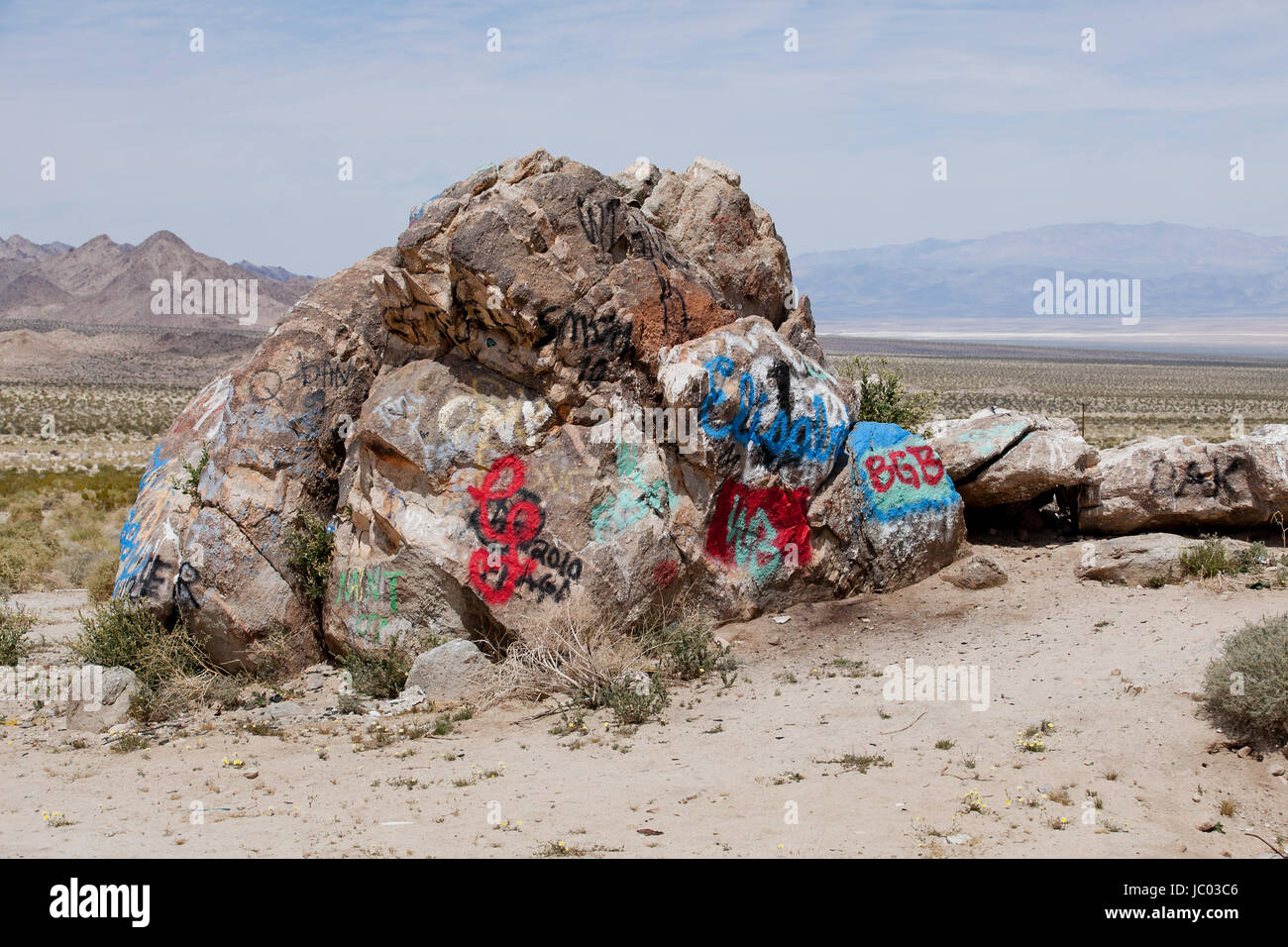 Graffiti verniciato a spruzzo sul boulder nel sud-ovest americano il paesaggio del deserto - Deserto Mojave, California USA Foto Stock