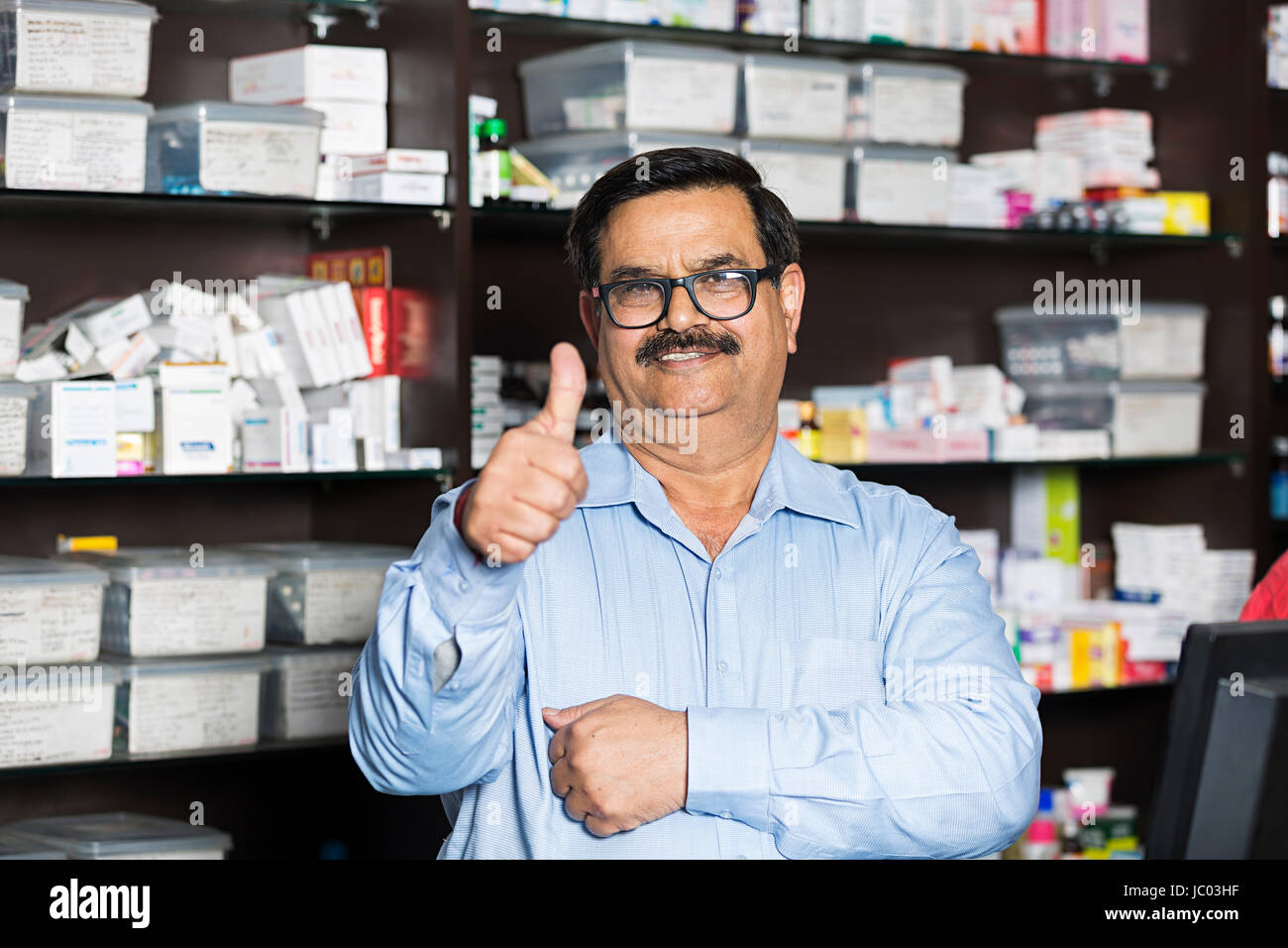 1 negoziante indiano uomo successo pollice in alto mostra in farmacia Foto Stock