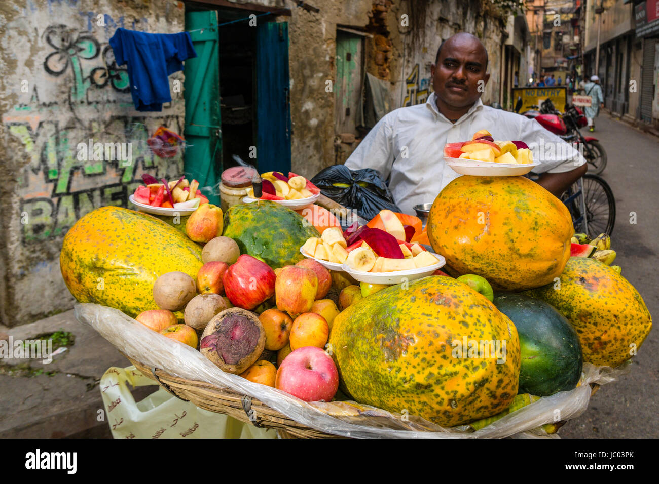 Un uomo è la vendita di frutta in un affollato mercato ortofrutticolo Street nel quartiere nuovo mercato Foto Stock