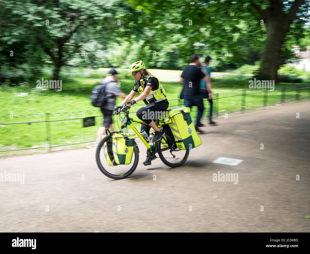 Una London Ambulance Service Bike Paramedic attraversa St James Park per una chiamata con luci blu lampeggianti. Parametri bici in movimento. Foto Stock