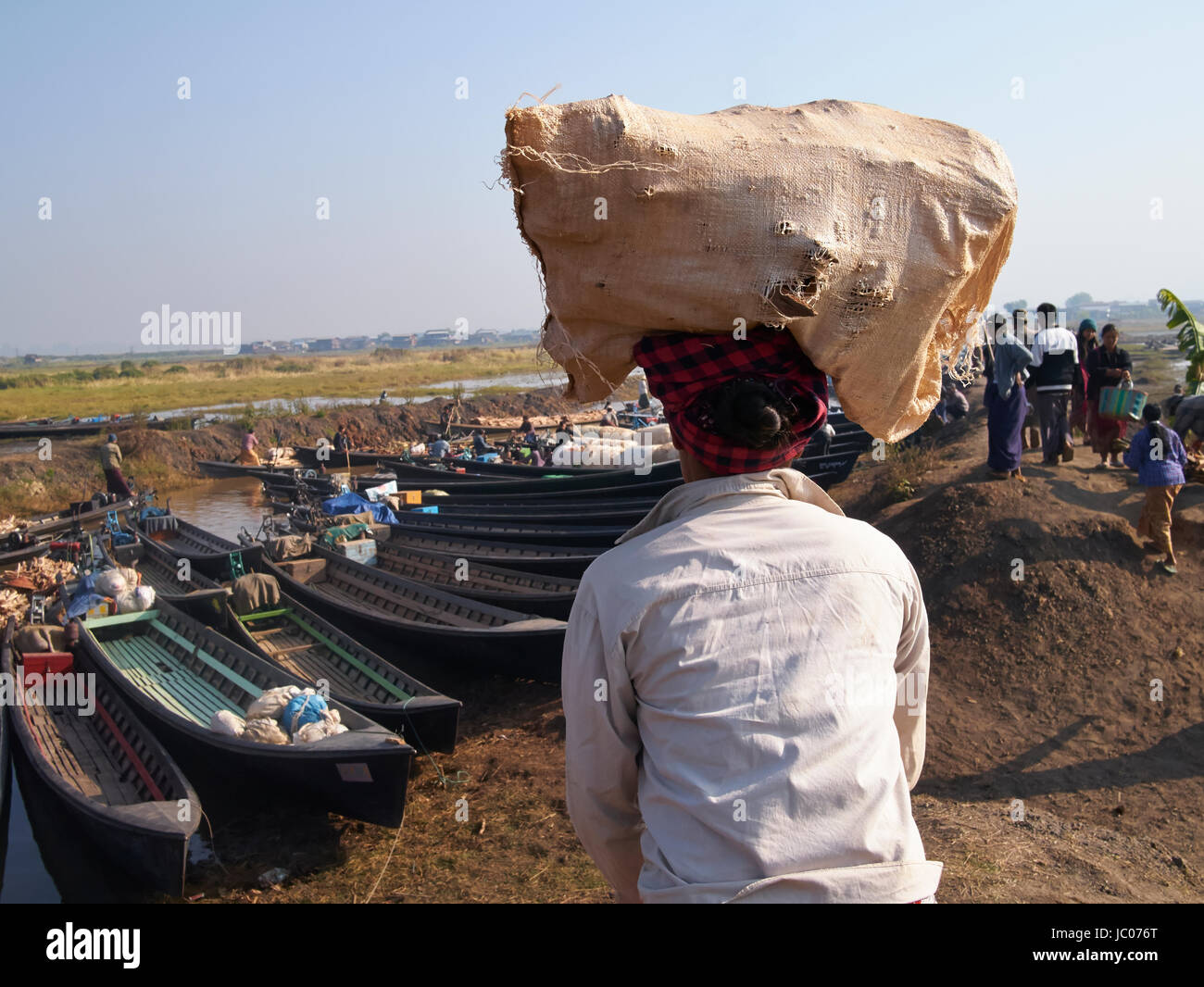Hilltribe portante locale fornisce sulla sua testa al Lago Inle Myanmar del mercato Foto Stock