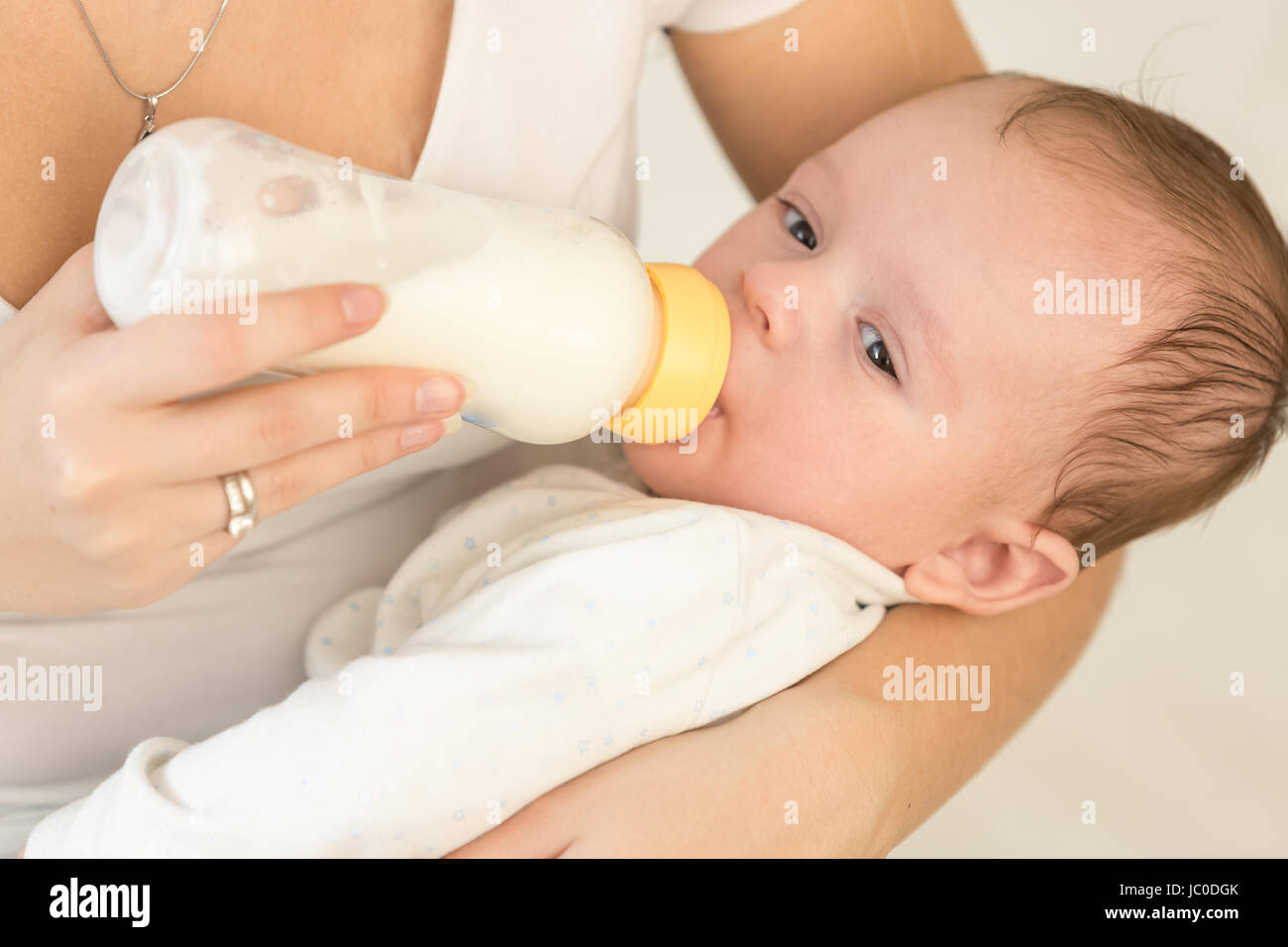 Closeup tonica Ritratto di giovane madre mentre tiene il suo bambino e l'alimentazione con latte Foto Stock