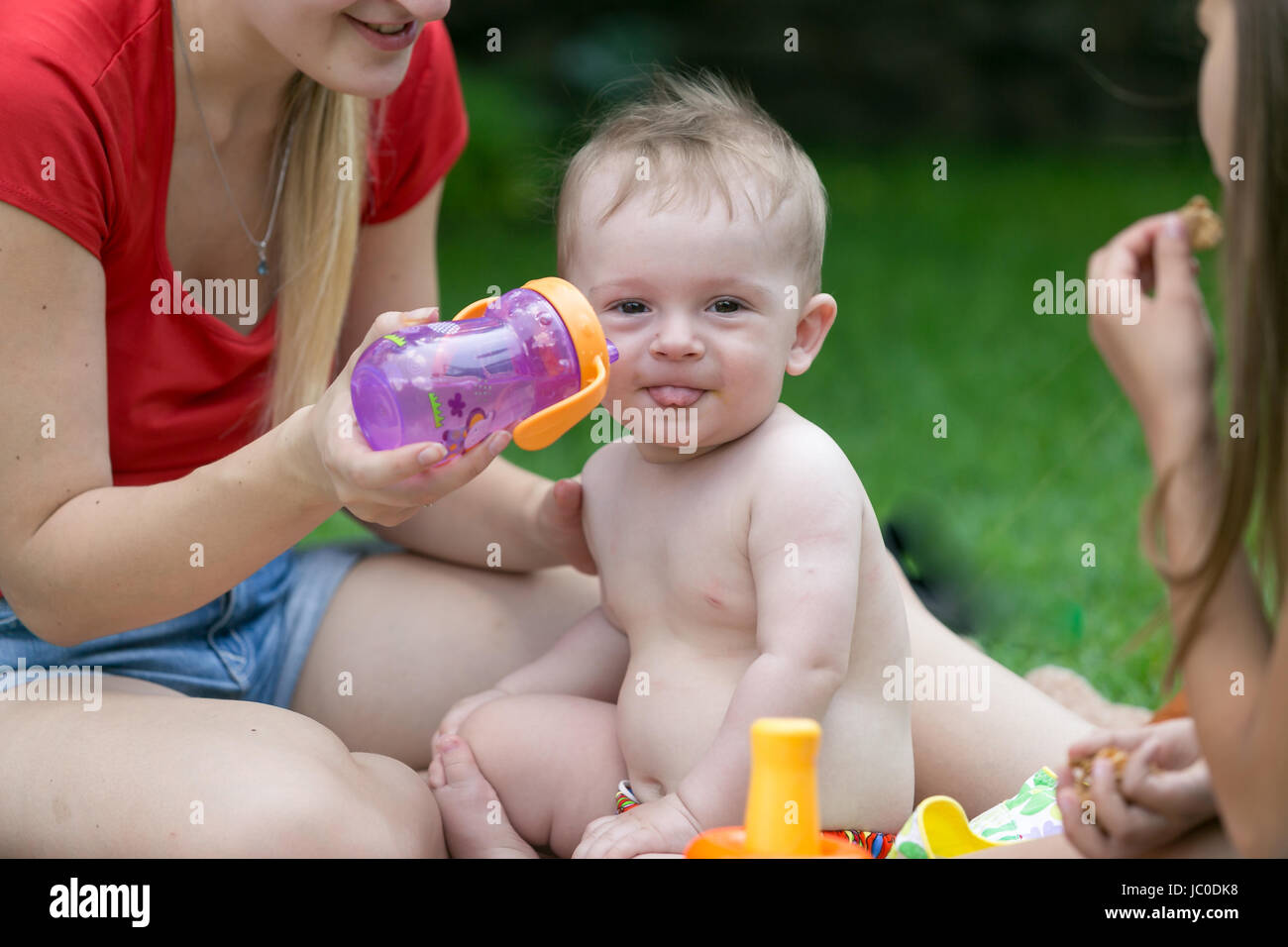 Closeup ritratto di adorabili baby boy acqua potabile dalla bottiglia a picnic nel giardino Foto Stock