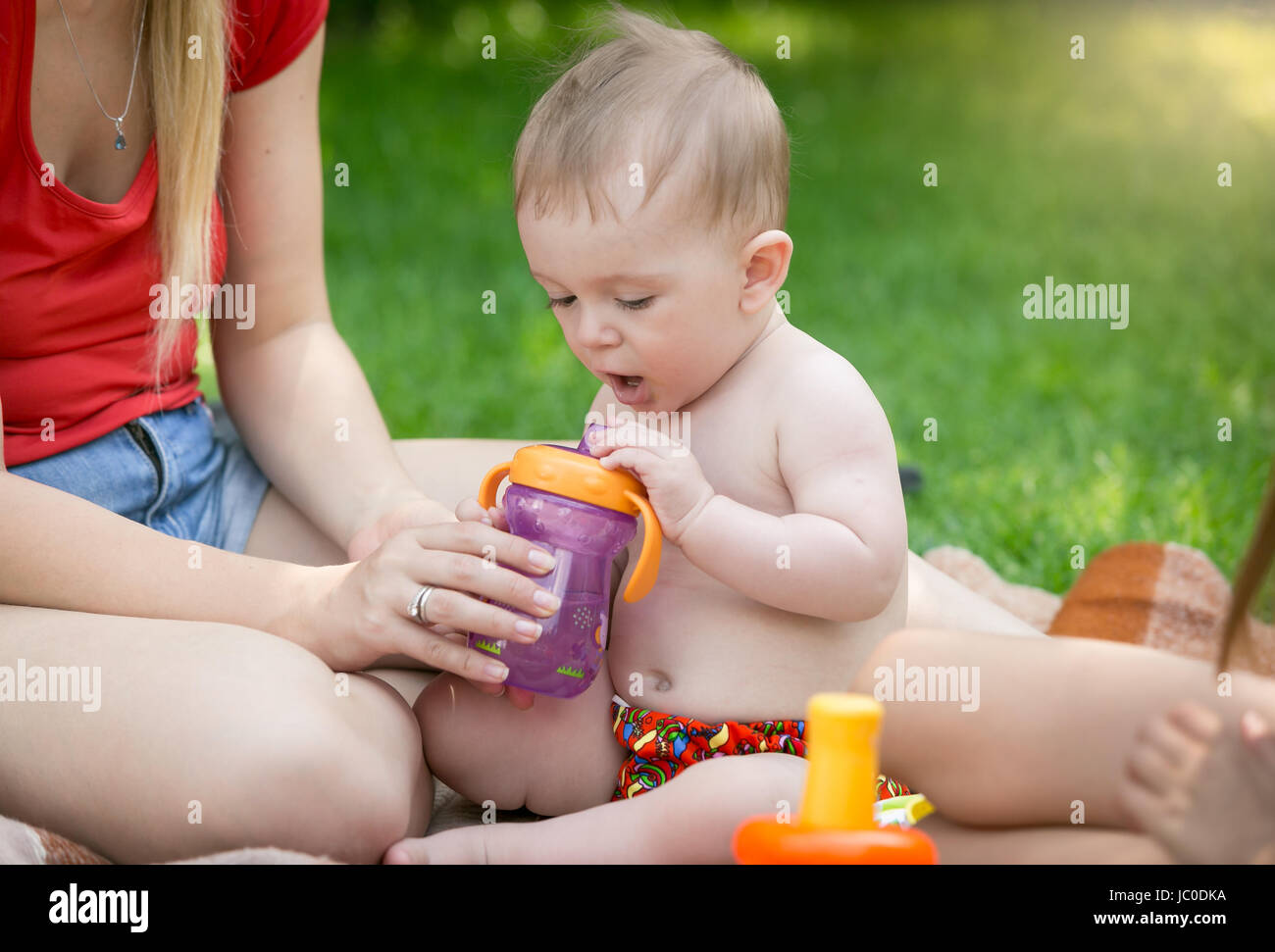 Ritratto di simpatici baby boy bere il succo da bottiglia a picnic al parco Foto Stock