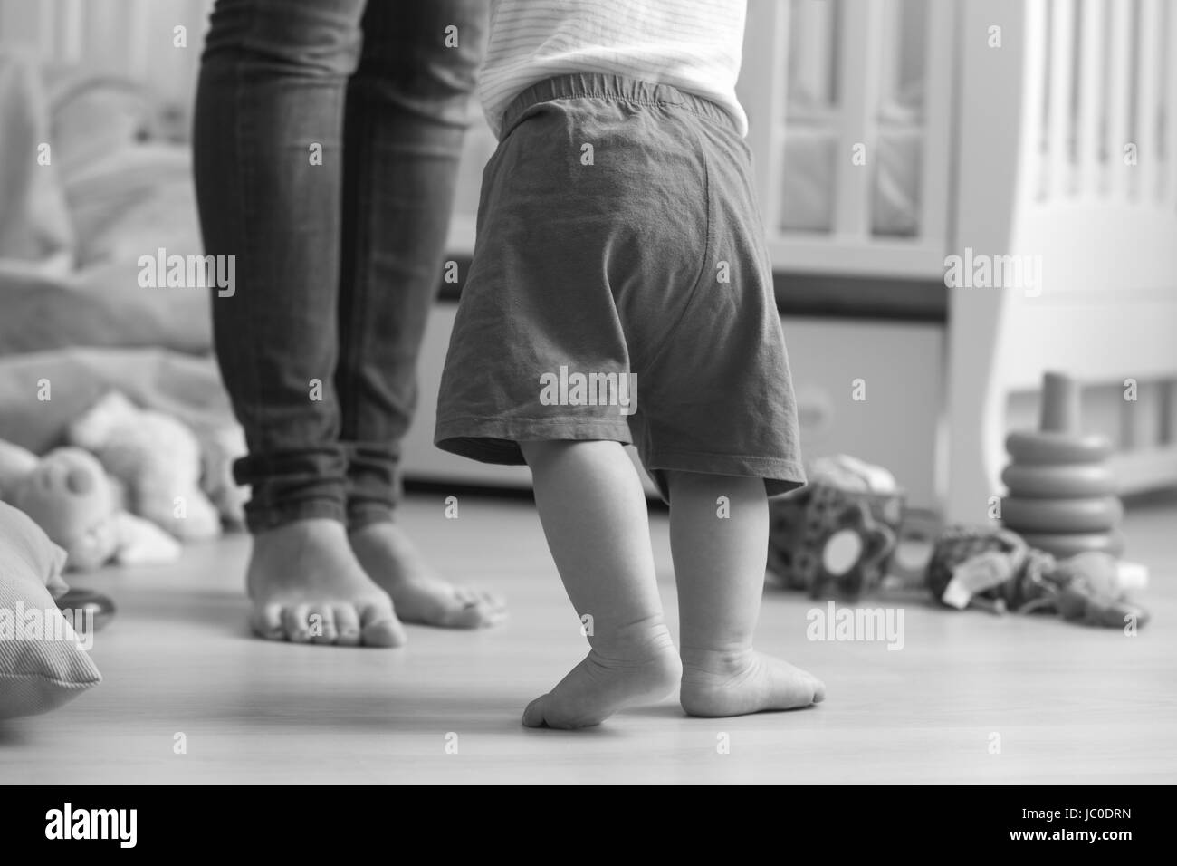 Primo piano immagine in bianco e nero di dieci mesi baby boy a piedi di sua madre in salotto Foto Stock