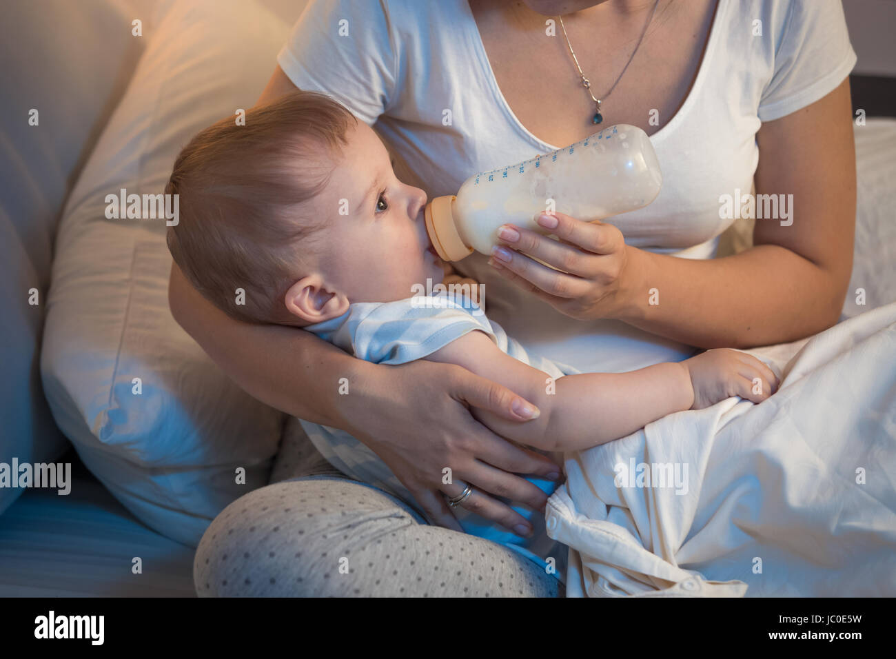 Closeup ritratto del magnifico bambino bere latte dal flacone di notte Foto Stock