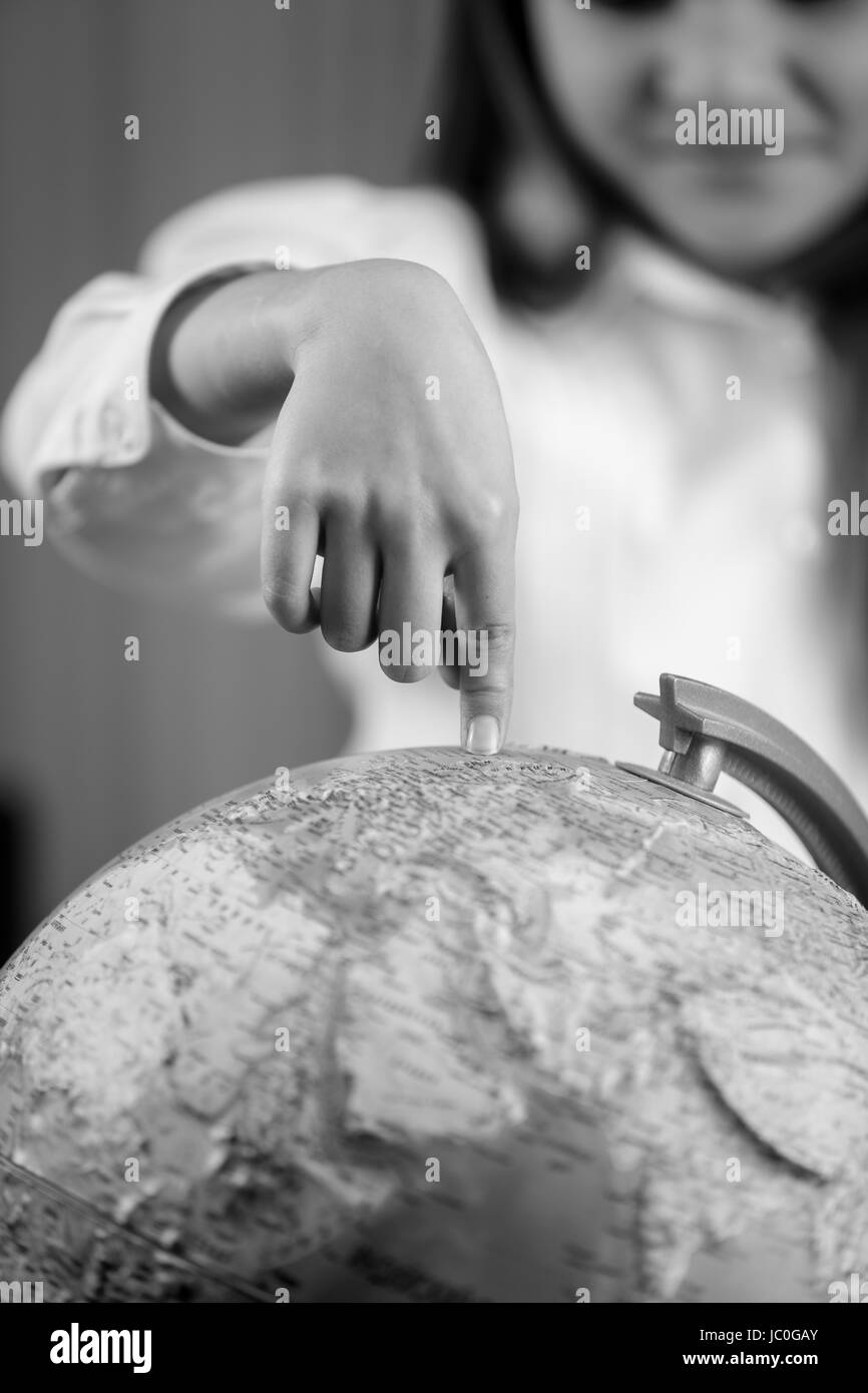 Primo piano immagine in bianco e nero di Cute girl puntando con il dito sul globo terrestre Foto Stock