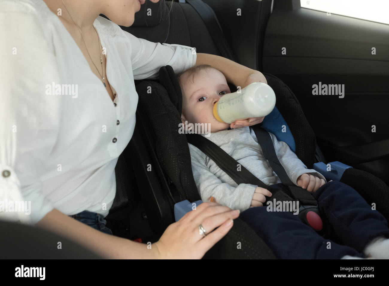 Ritratto di Madre dando il suo bambino il latte sulla vettura del sedile posteriore Foto Stock