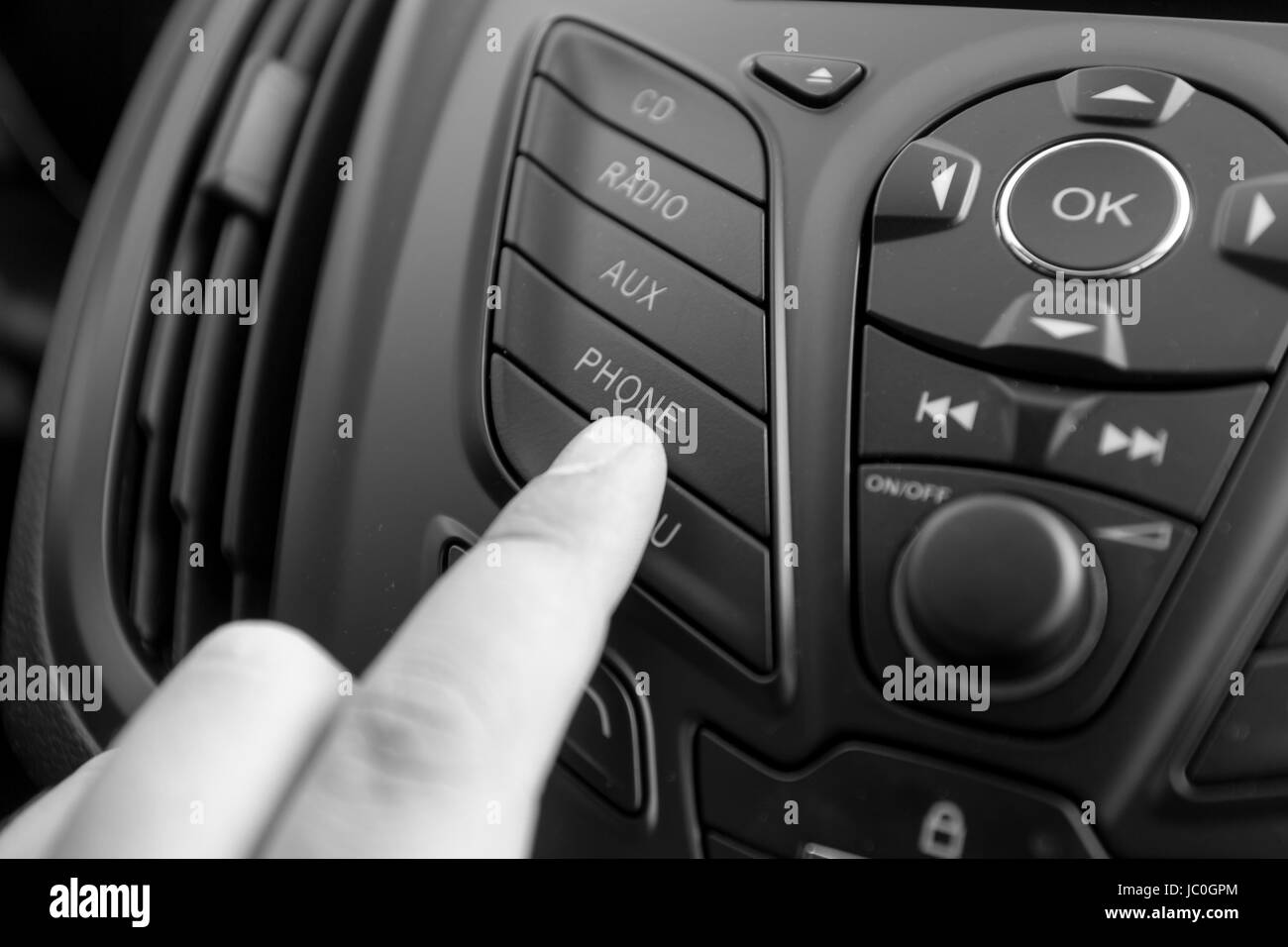 Bianco e nero closeup foto del conducente spingendo sul pulsante radio sul cruscotto Foto Stock