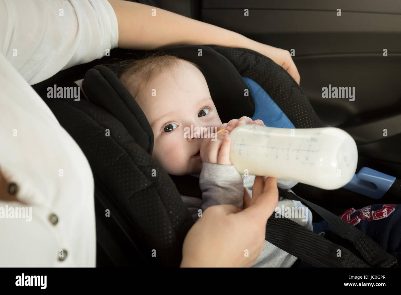 Closeup ritratto della madre del bambino di alimentazione in auto dalla bottiglia Foto Stock
