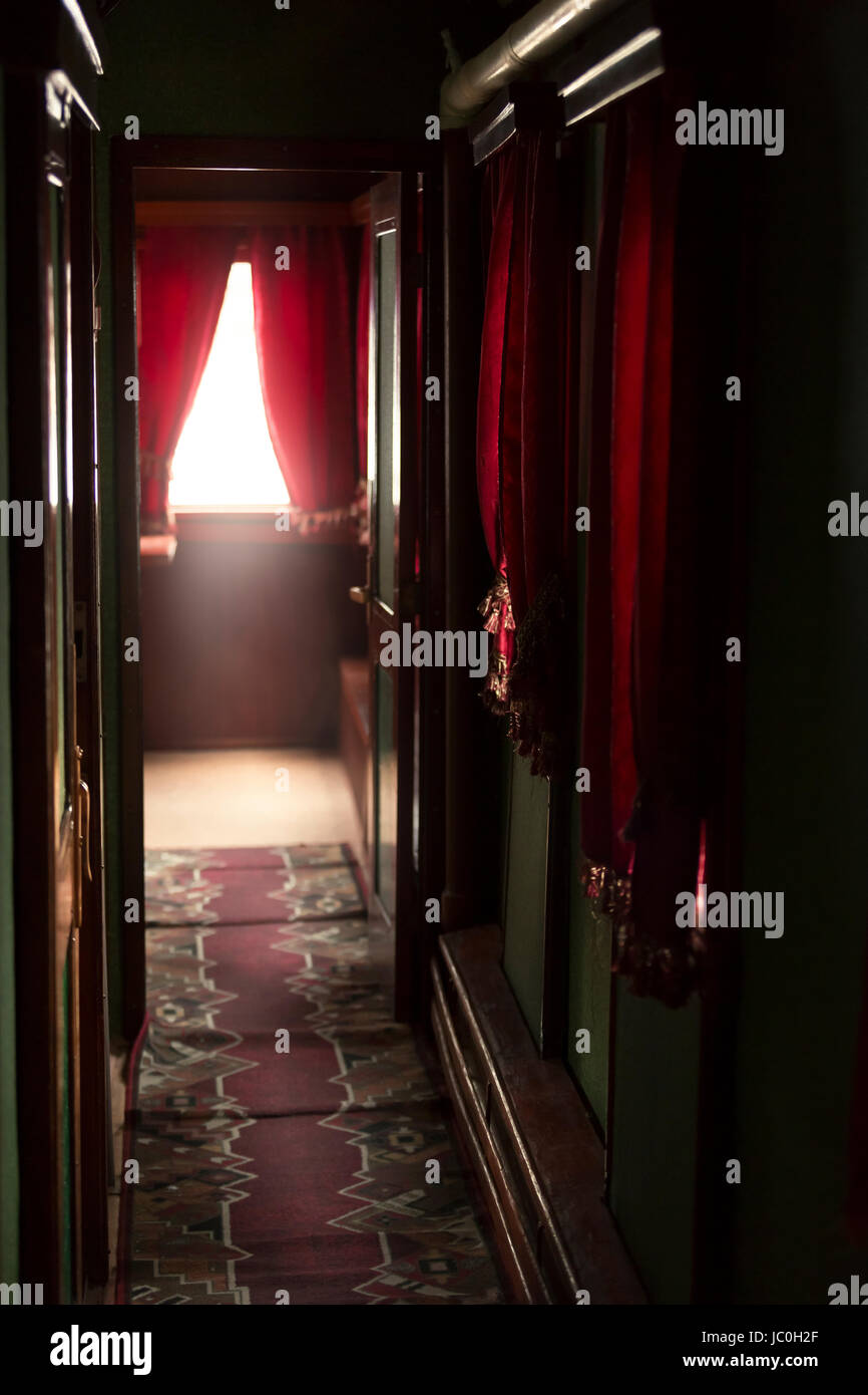 Interno del lussuoso treno vintage con un lungo corridoio e tendaggi rossi su windows Foto Stock