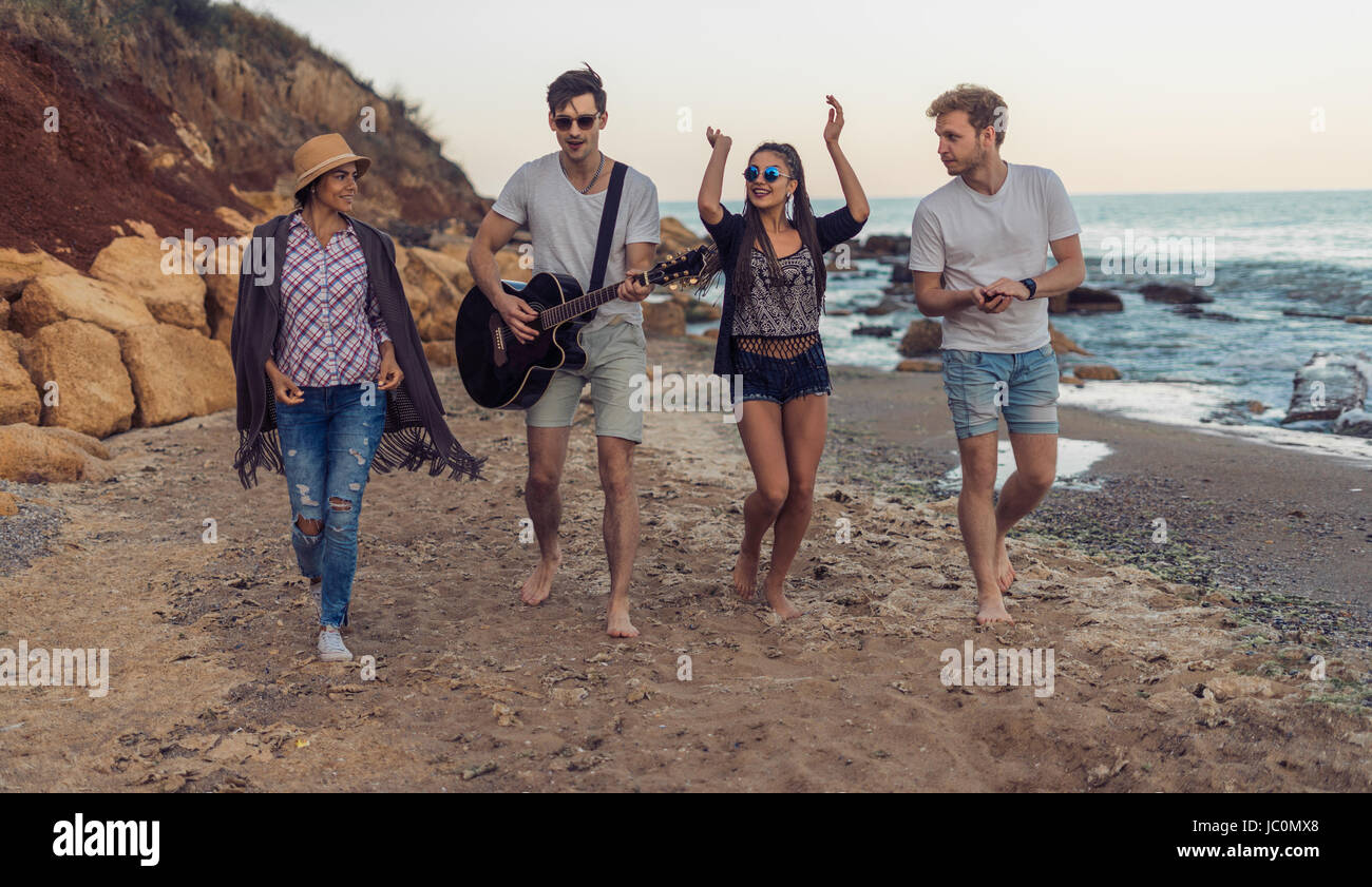 Un gruppo di giovani e allegro amici camminando sulla spiaggia Foto Stock