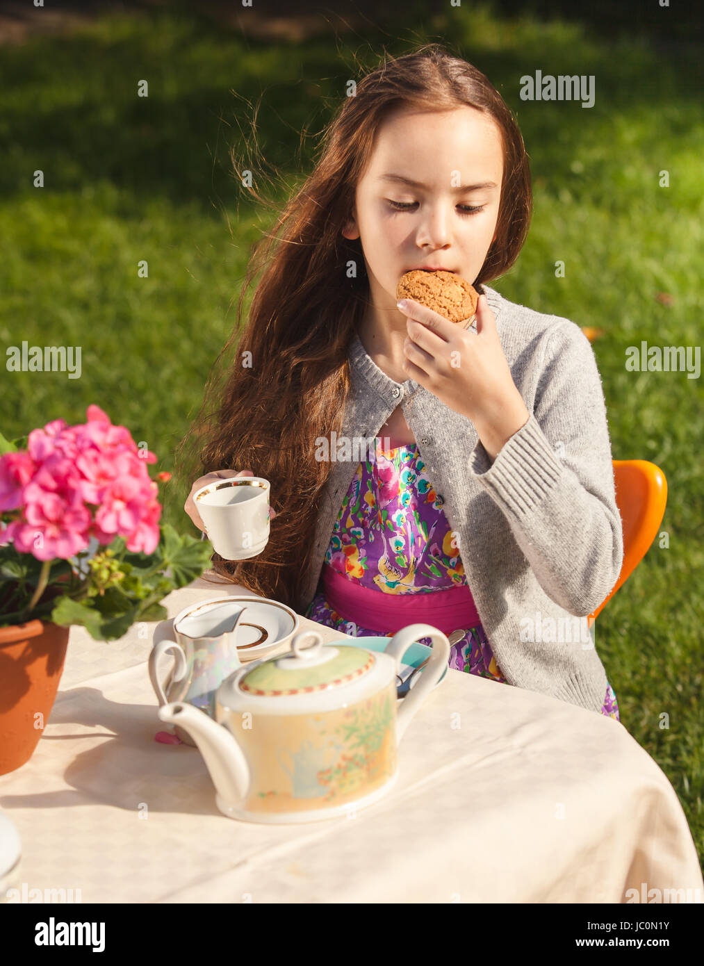 Ritratto di bella ragazza di fare colazione in cantiere e mordere cookie Foto Stock