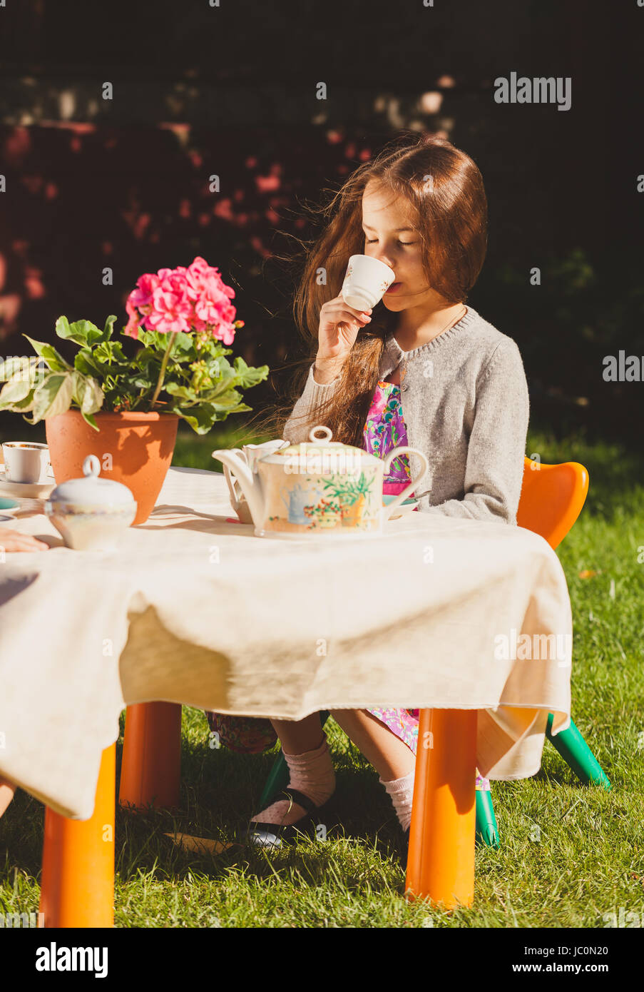 Bella ragazza carina bere il tè al tavolo giocattolo in cantiere Foto Stock
