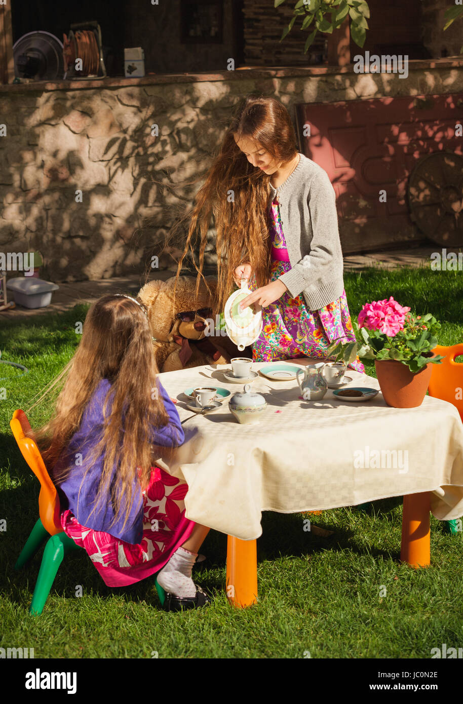 Bella ragazza versando il tè a sua sorella a toy tea party Foto Stock