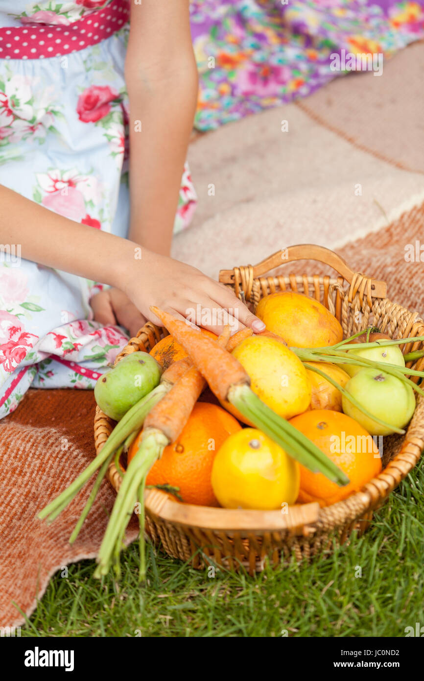 Closeup shot della ragazza seduta su erba e tenendo la carota al di fuori del cestello Foto Stock