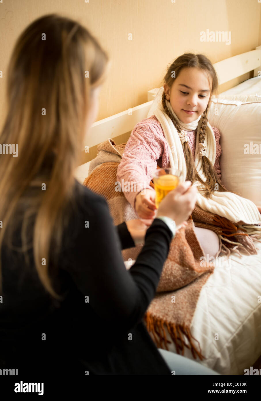 Ritratto di Madre premurosa dando il tè caldo ai malati la figlia in appoggio a letto Foto Stock