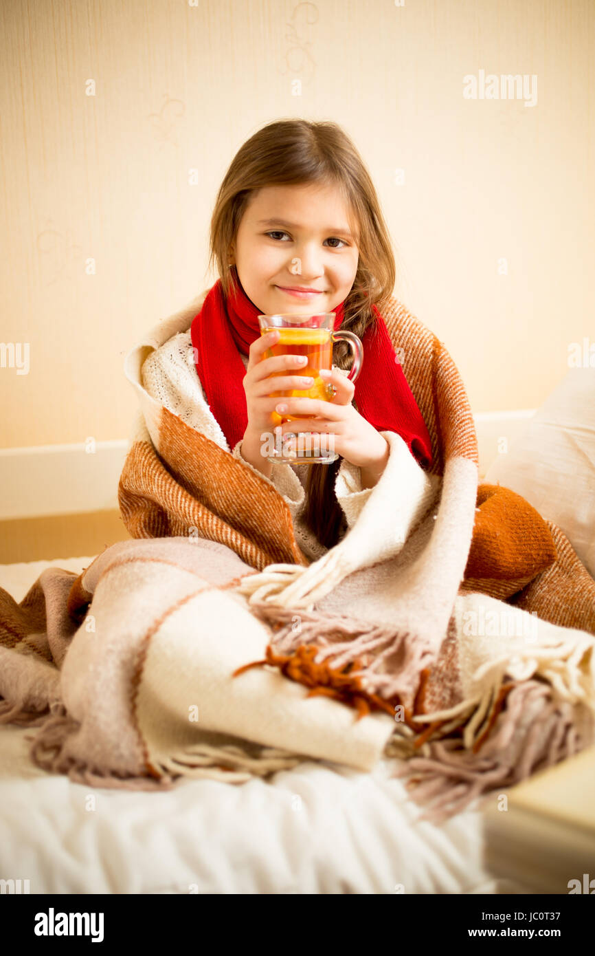 Ritratto di ragazza carina contemplati nella coperta di bere il tè caldo con limone a letto Foto Stock