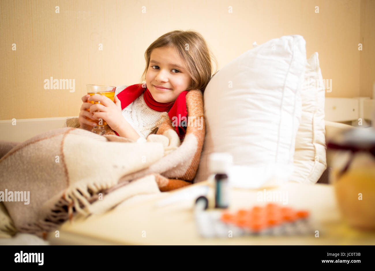 Bambina catturati flu e di bere il tè caldo con limone a letto Foto Stock