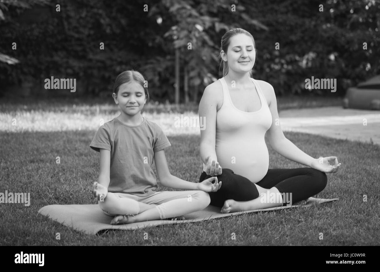 Immagine in bianco e nero di gravidanza madre e figlia meditando in posizione di parcheggio Foto Stock