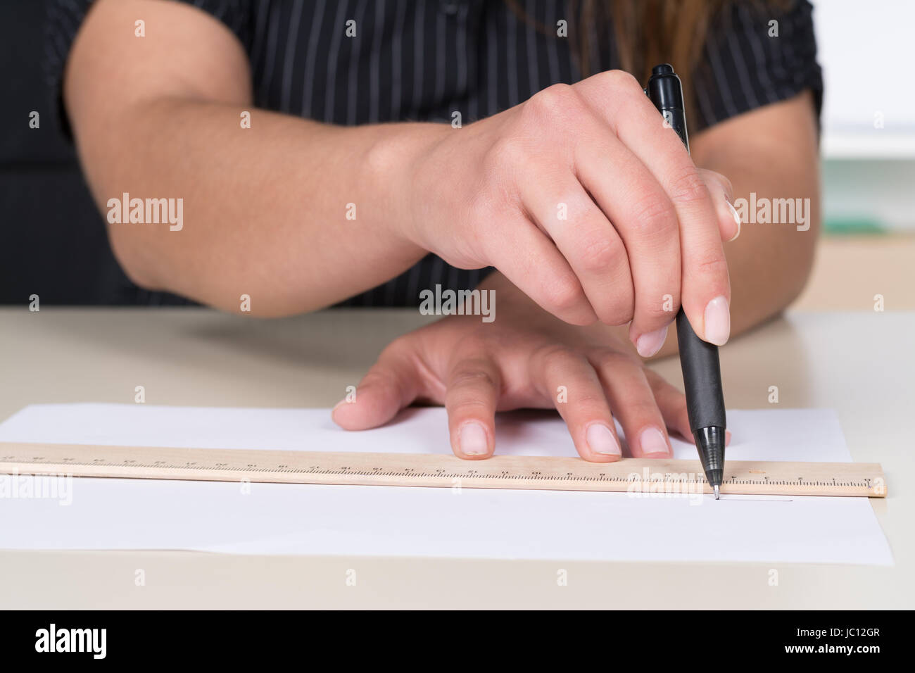 Frau zeichnet eine Linie mit Lineal und Stift am Schreibtisch. Foto Stock