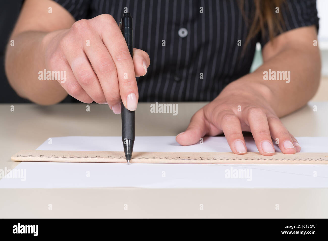 Frau zeichnet eine Linie mit Lineal und Stift am Schreibtisch. Foto Stock