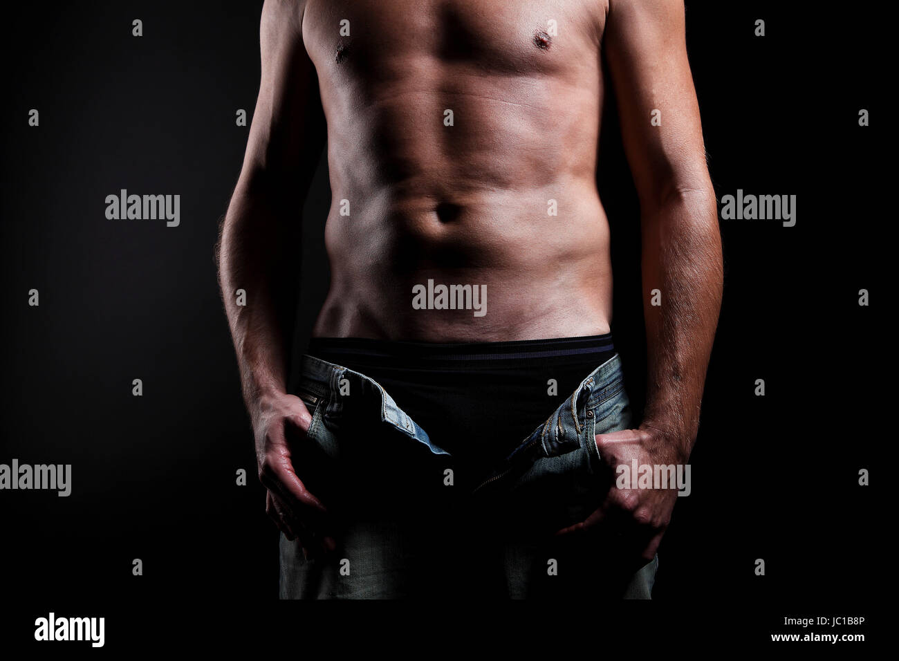 Attraente uomo shirtless davanti a sfondo nero Foto Stock