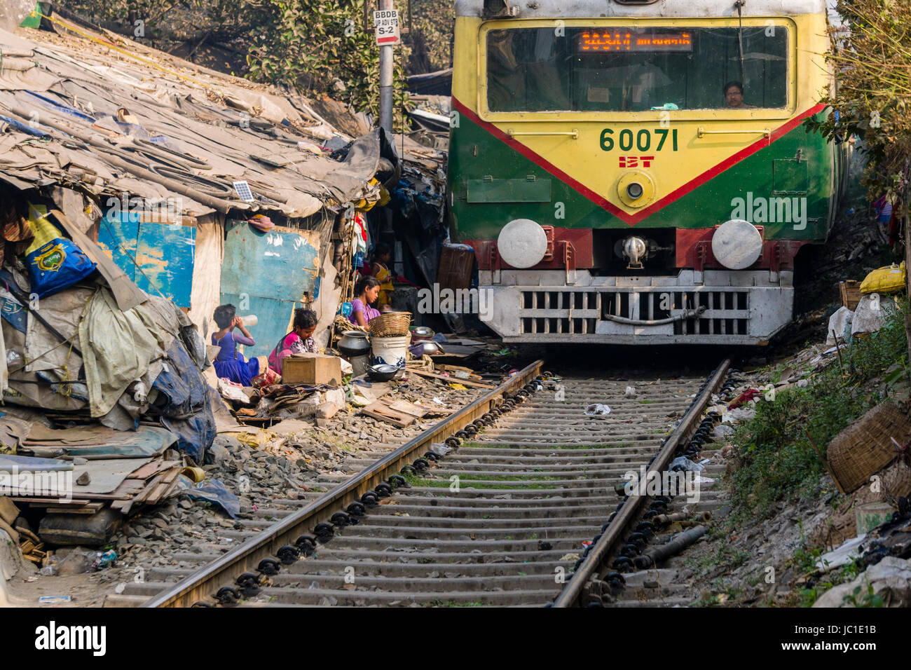 Il numero di abitazioni e di capanne in Cina Bazar delle baraccopoli sono situati proprio accanto ai binari della ferrovia, un treno è passante Foto Stock