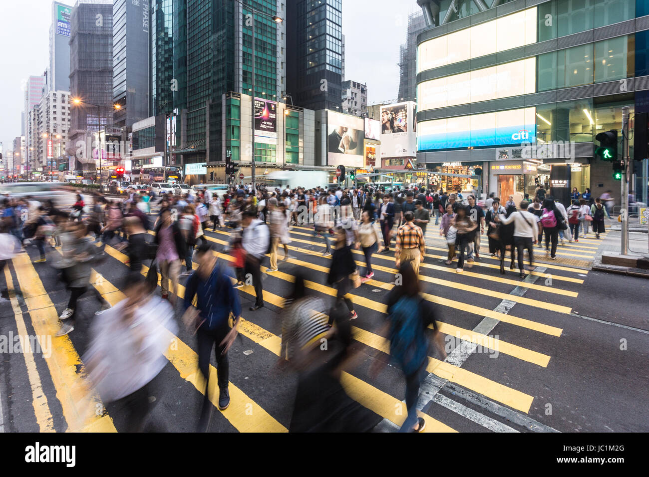 HONG KONG - Aprile 26, 2017: persone, catturata con movimento sfocate, cross Nathan Road in molto affollato Mong Kok quartiere dello shopping di Kowloon. Foto Stock