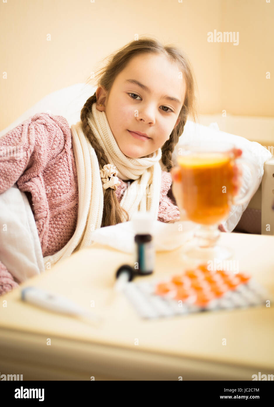 Ritratto di piccoli malati ragazza distesa nel letto di prendere tazza di tè con il limone Foto Stock